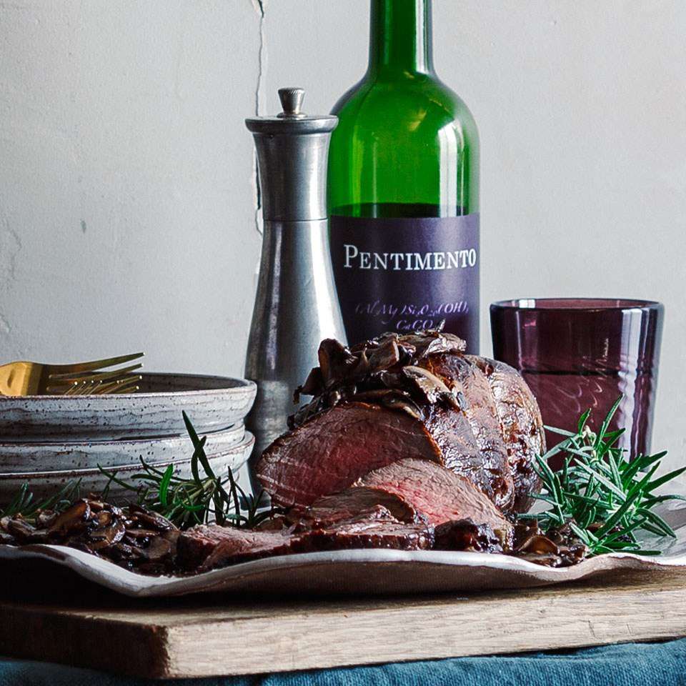 roast beef on a table with a bottle of wine