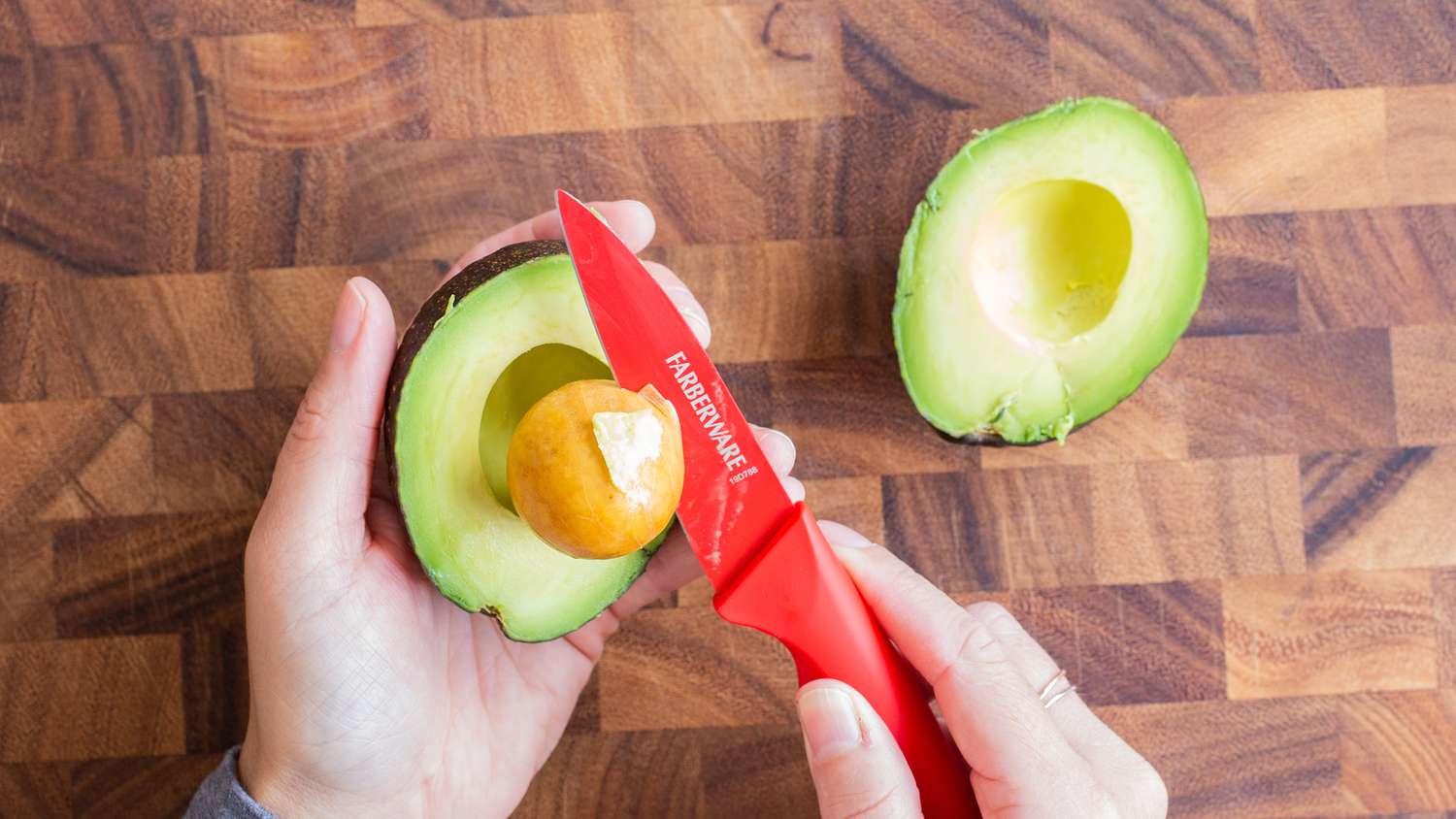 pitting an avocado with a red knife