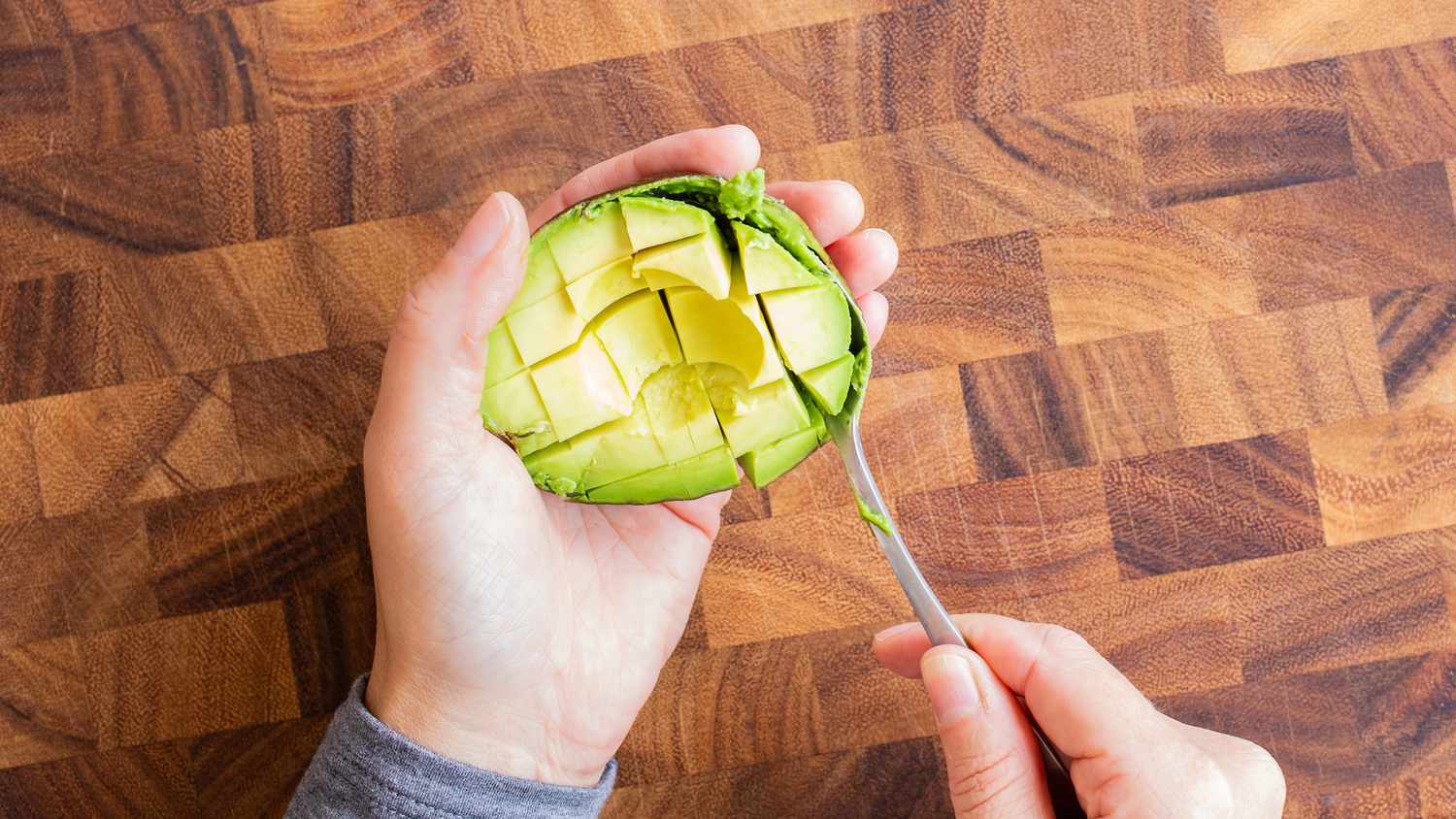 scooping diced avocado with a spoon