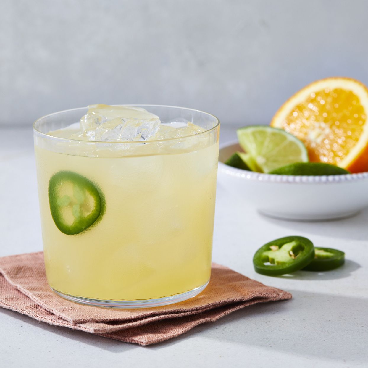 margarita in a cocktail glass garnished with jalapeno slices and citrus slices
