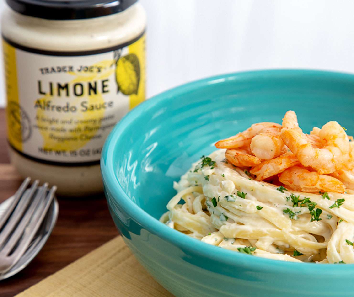 Trader Joe's Limone Alfredo Sauce in a jar with a bowl of pasta with shrimp