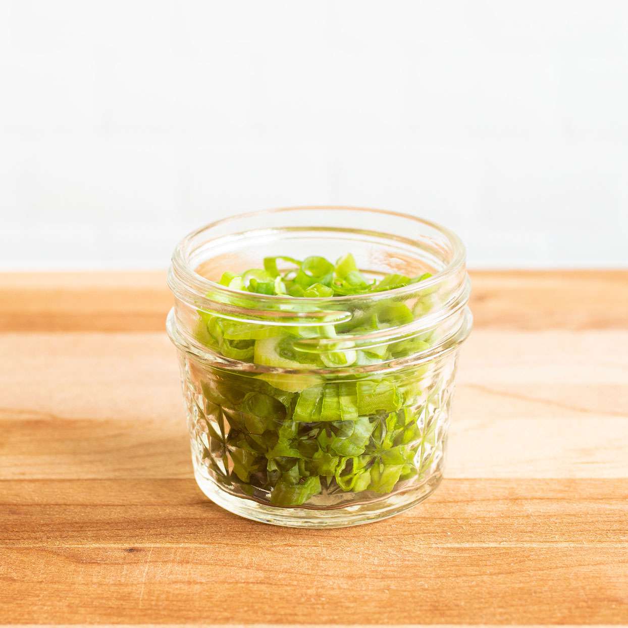 Sliced green onion rounds in a small jar