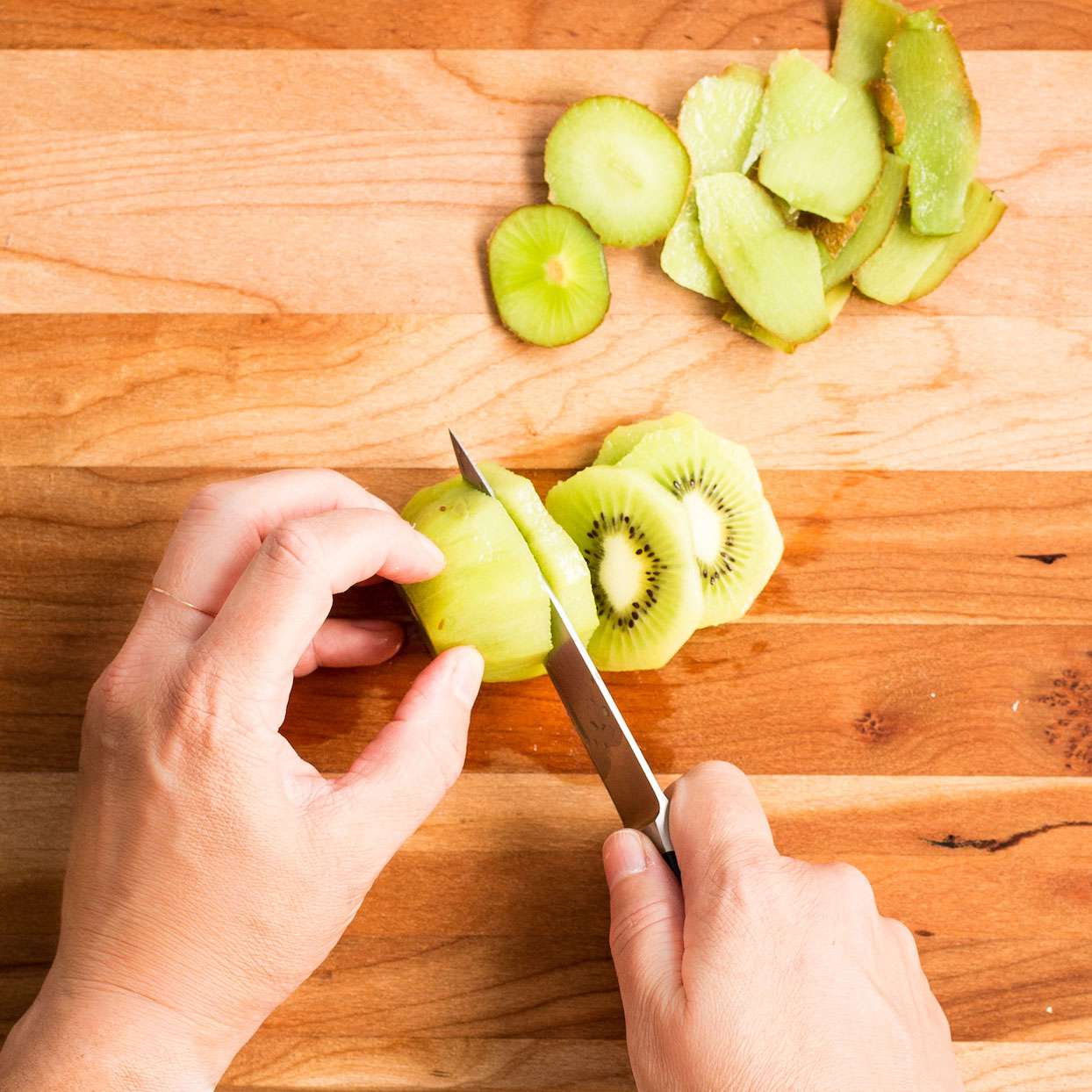 cutting kiwi on a wooden cutting board