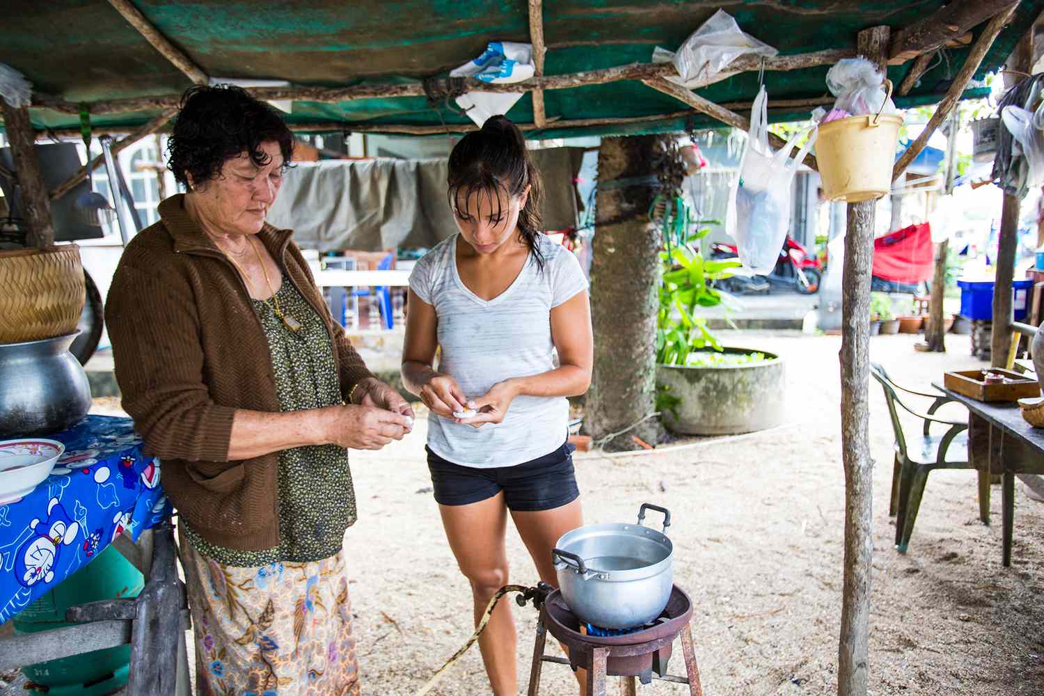 Older and younger woman cooking together in an outdoor kitchen