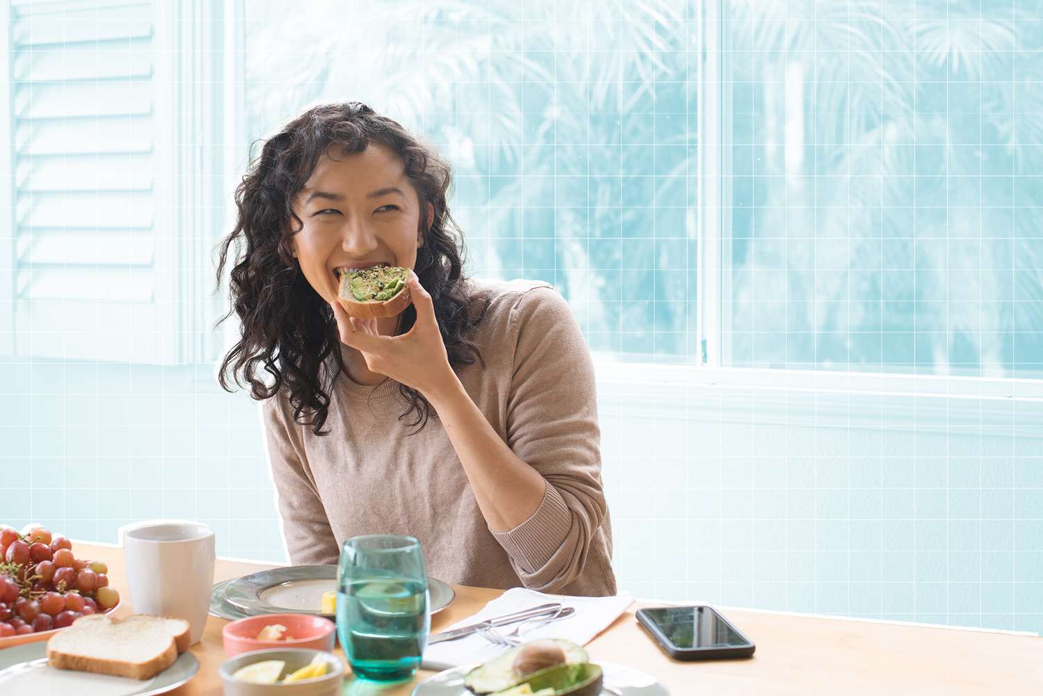 Young woman eating avocado toast at home