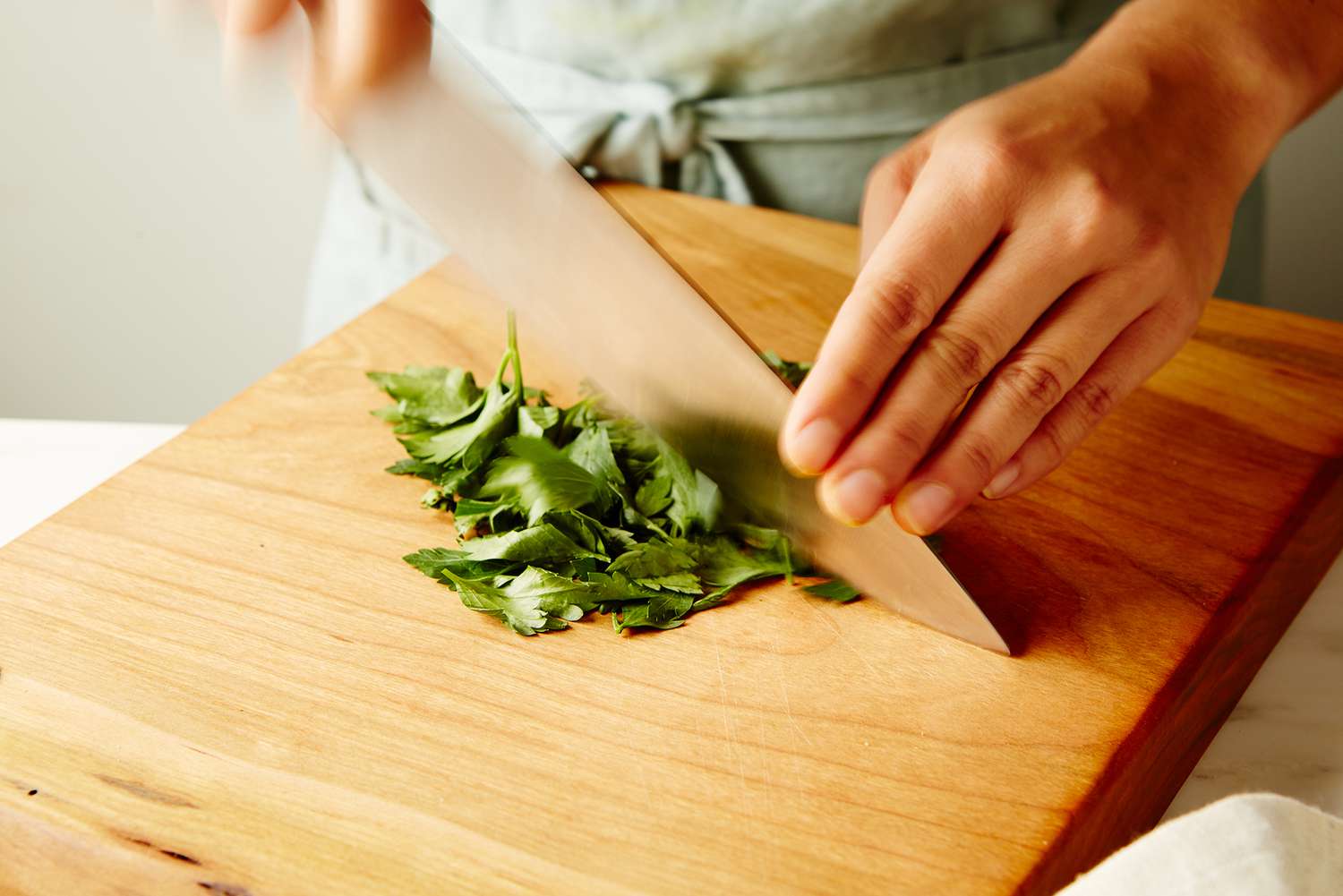 Midsection of person cutting parsley in kitchen