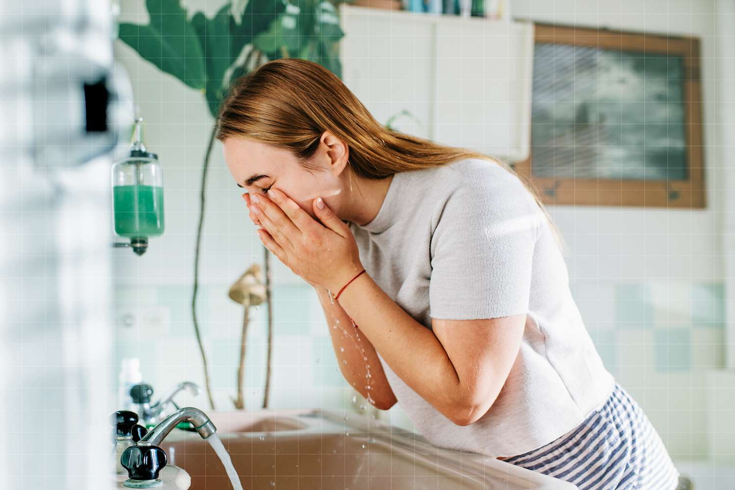 Woman in bathroom washing face
