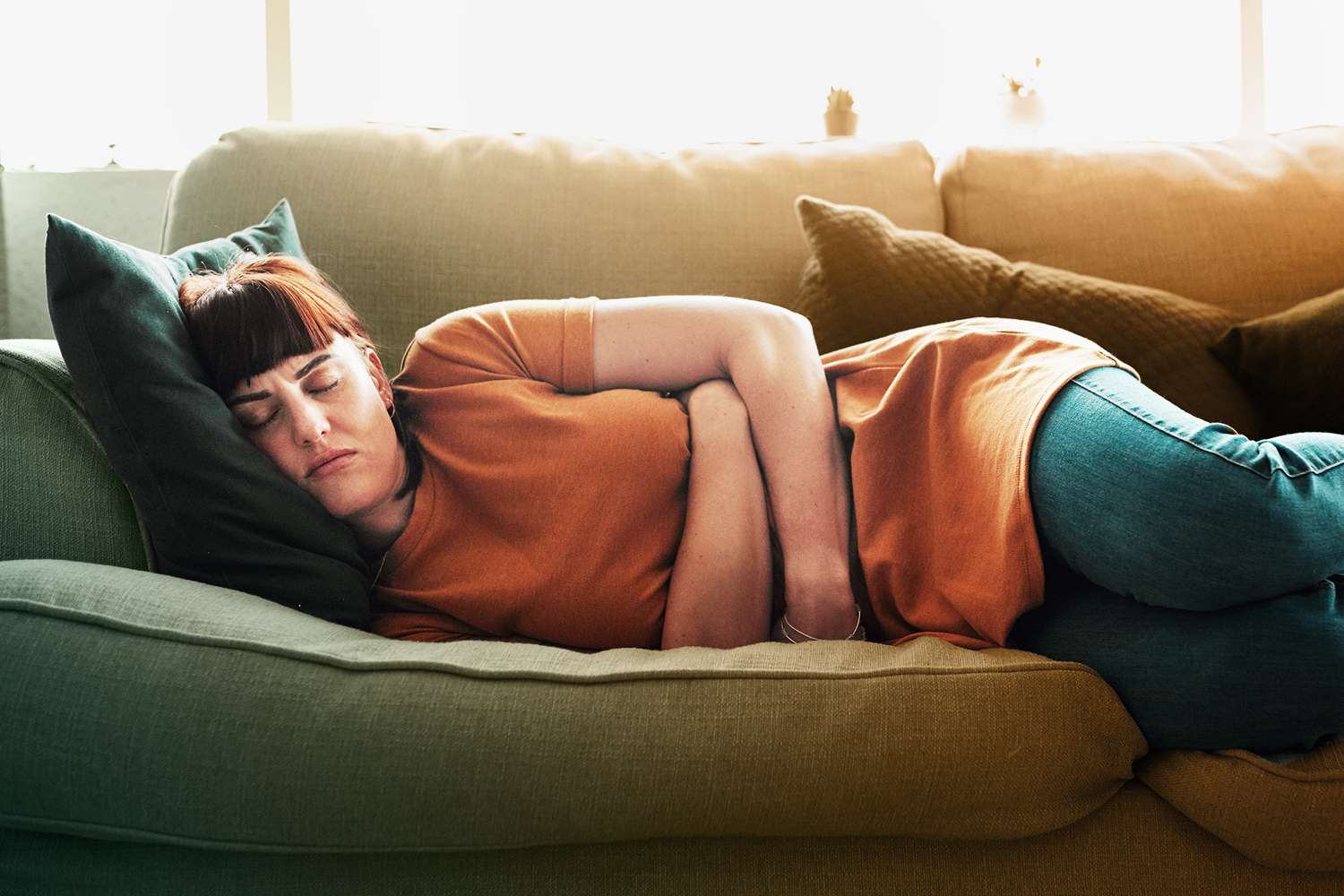 woman with a stomach ache laying on a couch