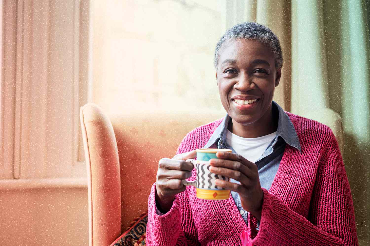 Portrait of cheerful woman holding mug and smiling towards camera