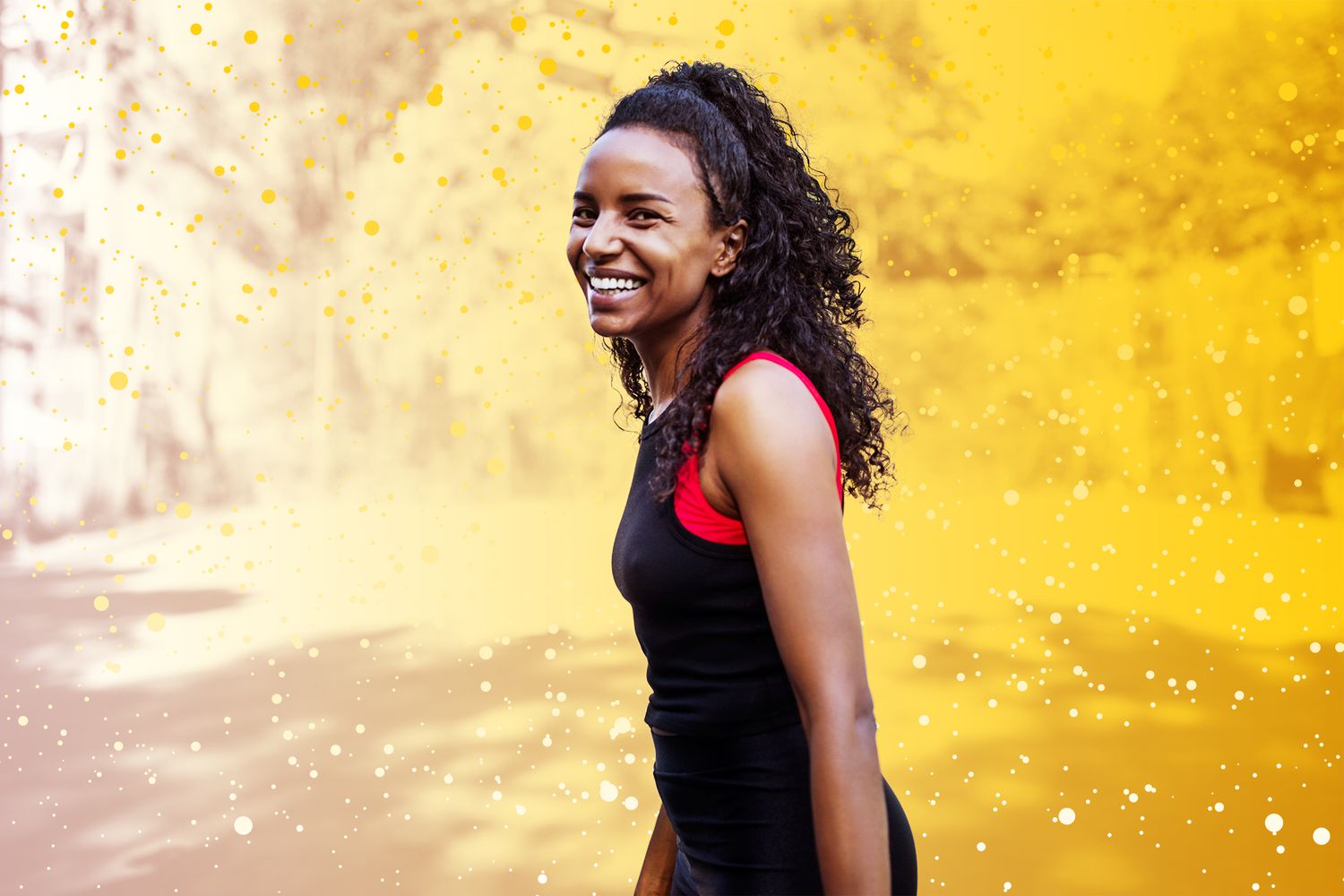 A woman smiling outside while wearing workout clothing