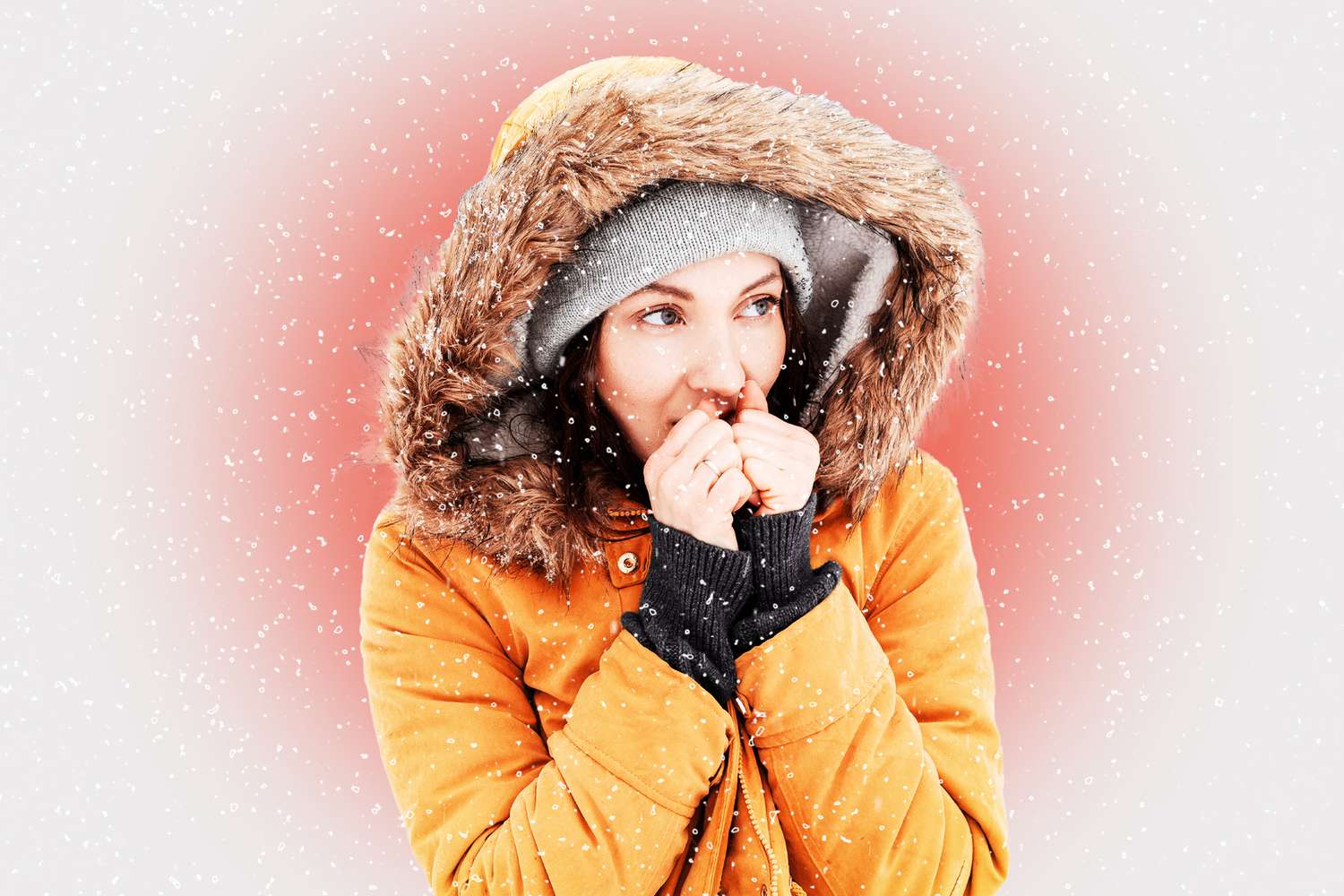 A woman looking cold in a yellow winter jacket. Snow is falling and a red gradient is behind her