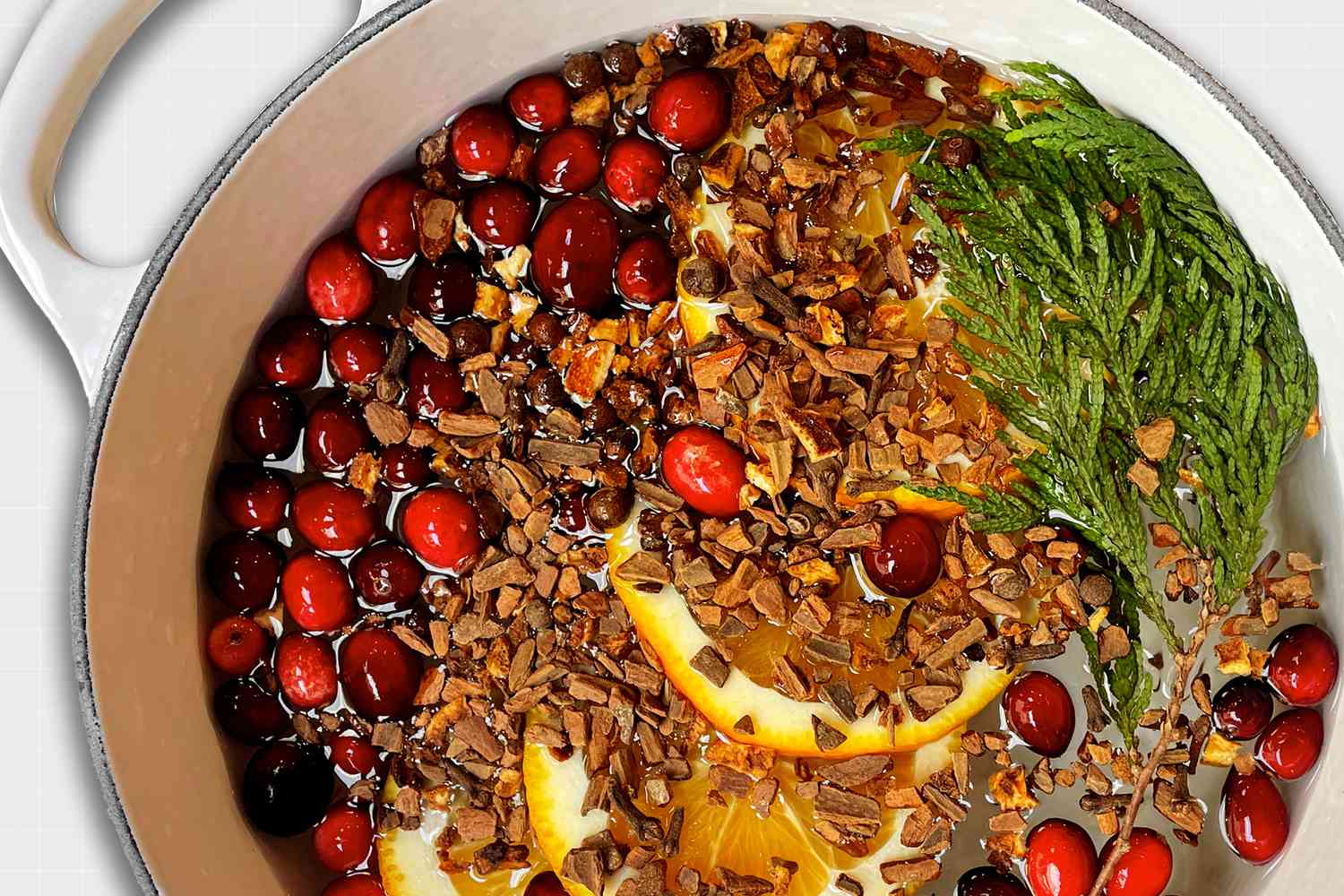 A simmer pot full of oranges, cranberries, a pine branch and cinnamon