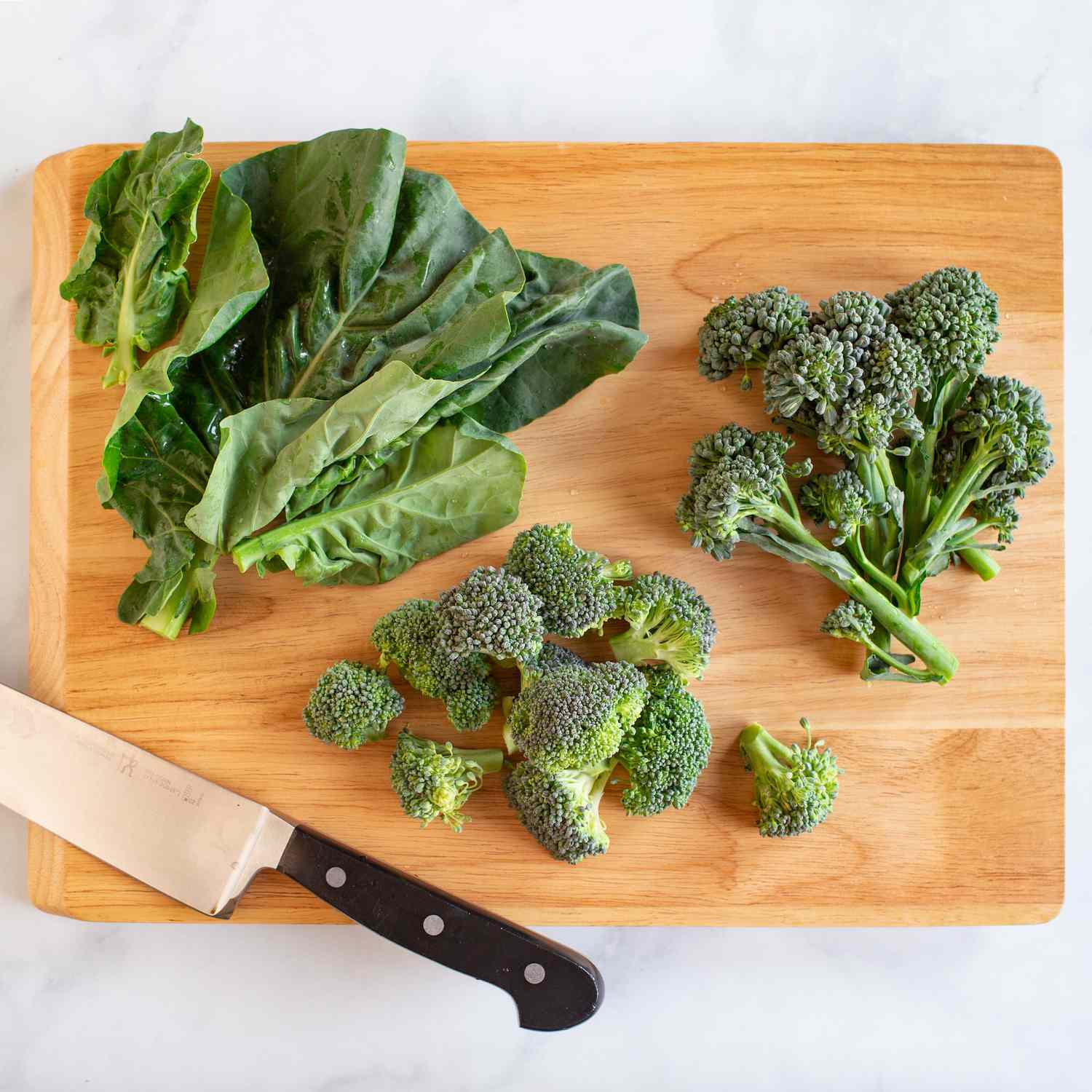 3 different. types of cut broccoli on a wood cutting board with a knife