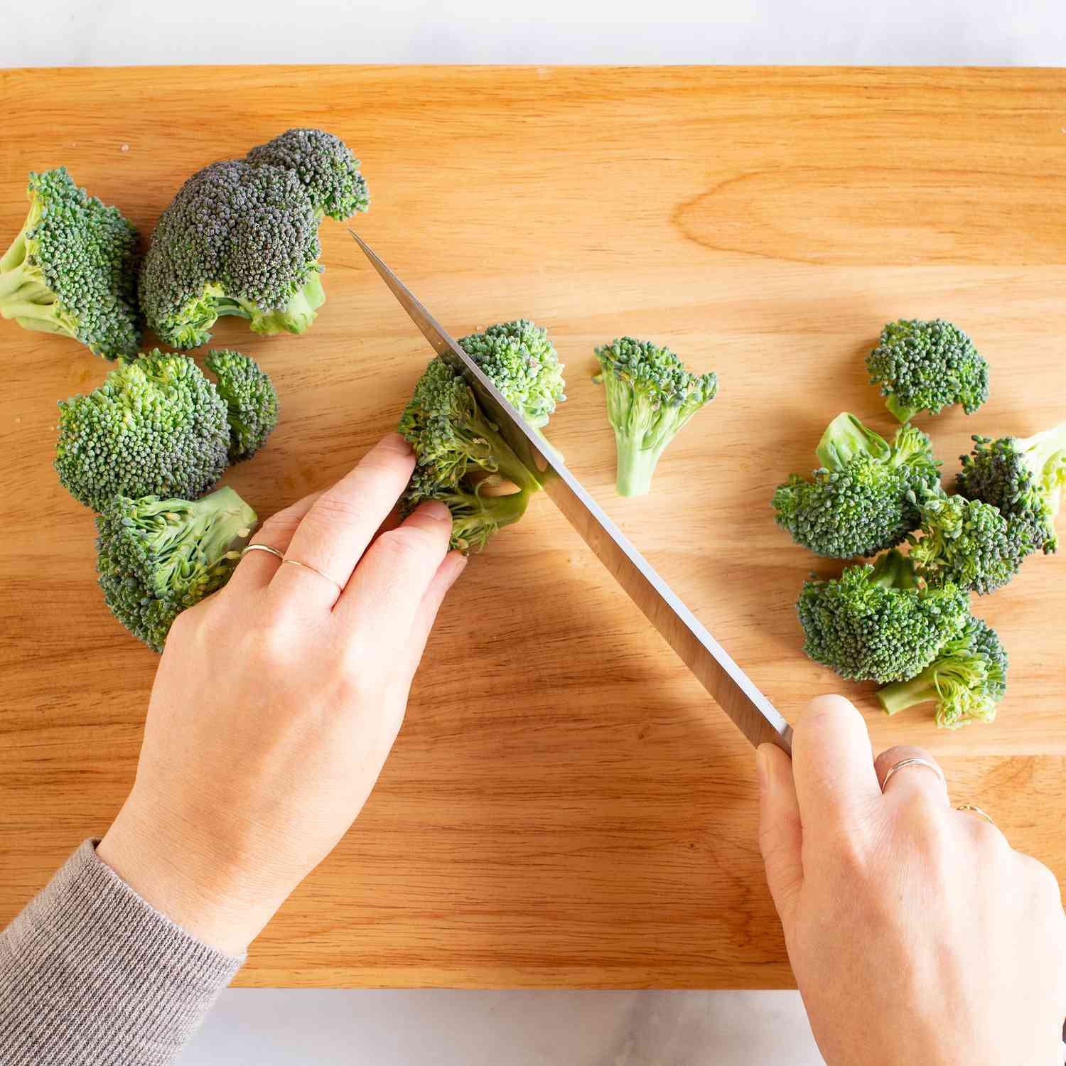 Small broccoli pieces being cut on a cutting board
