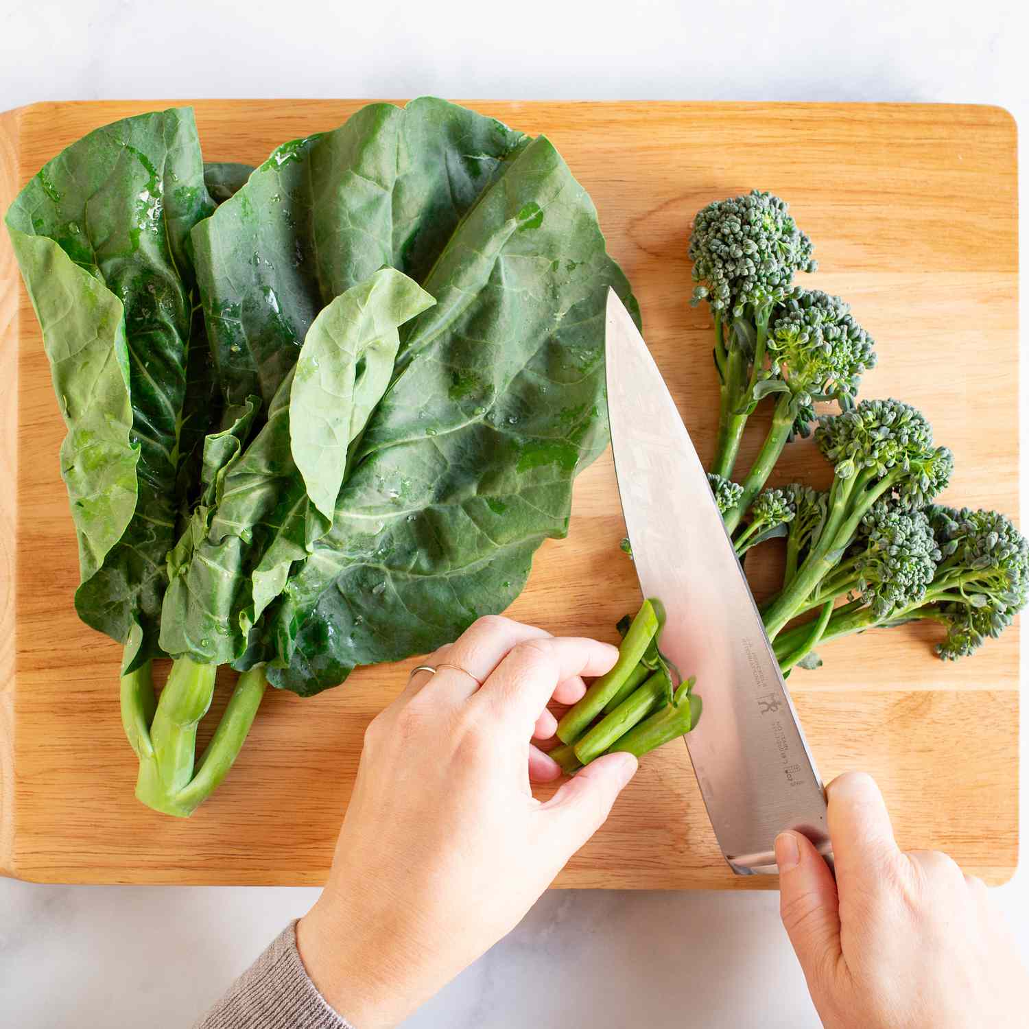 Chinese broccoli and broccoli rabe being cut on a cutting board