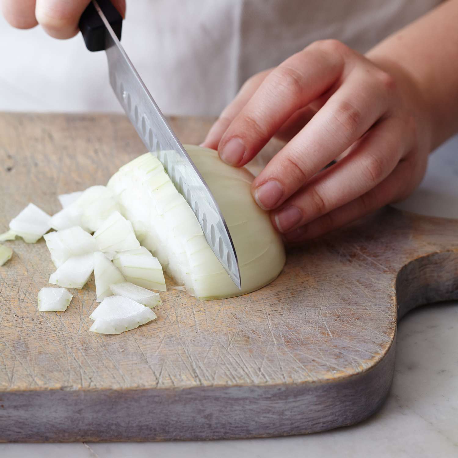 Midsection of woman chopping white onion on cutting board
