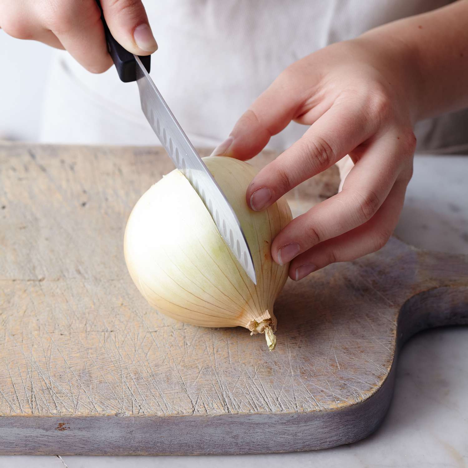 Midsection of woman cutting white onion on table