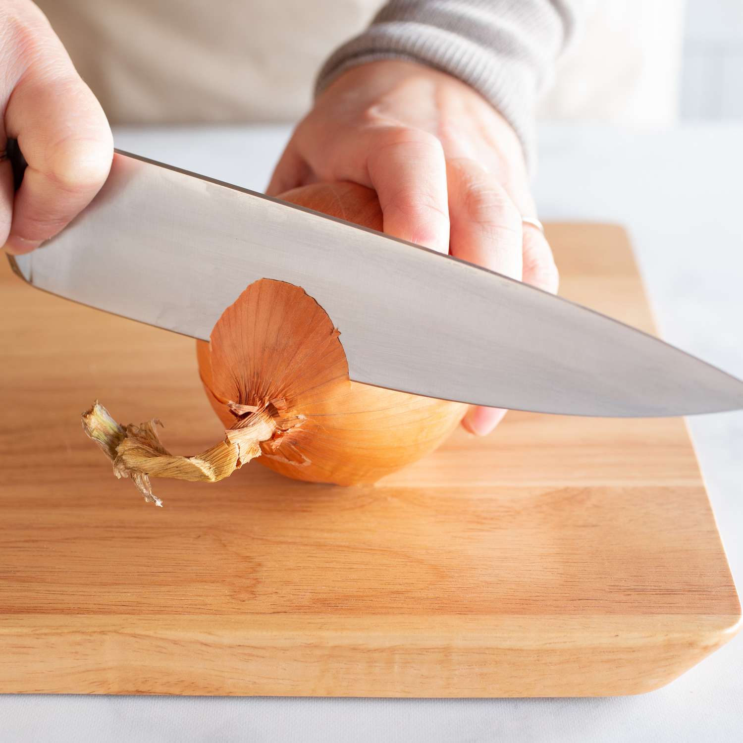 A knife cutting off the end of an onion