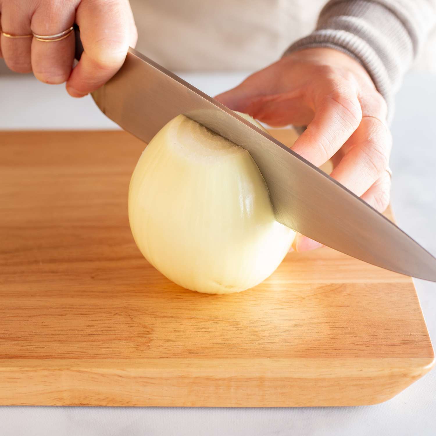 Close up of a knife being used to cut an onion in half