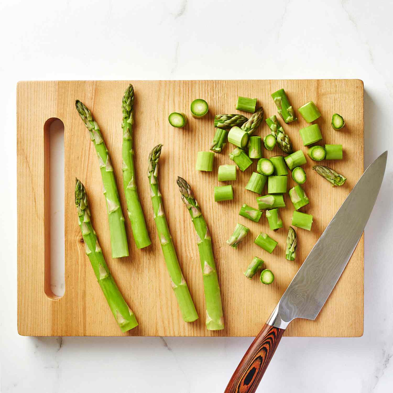 Asparagus and a knifee on a wood cutting board