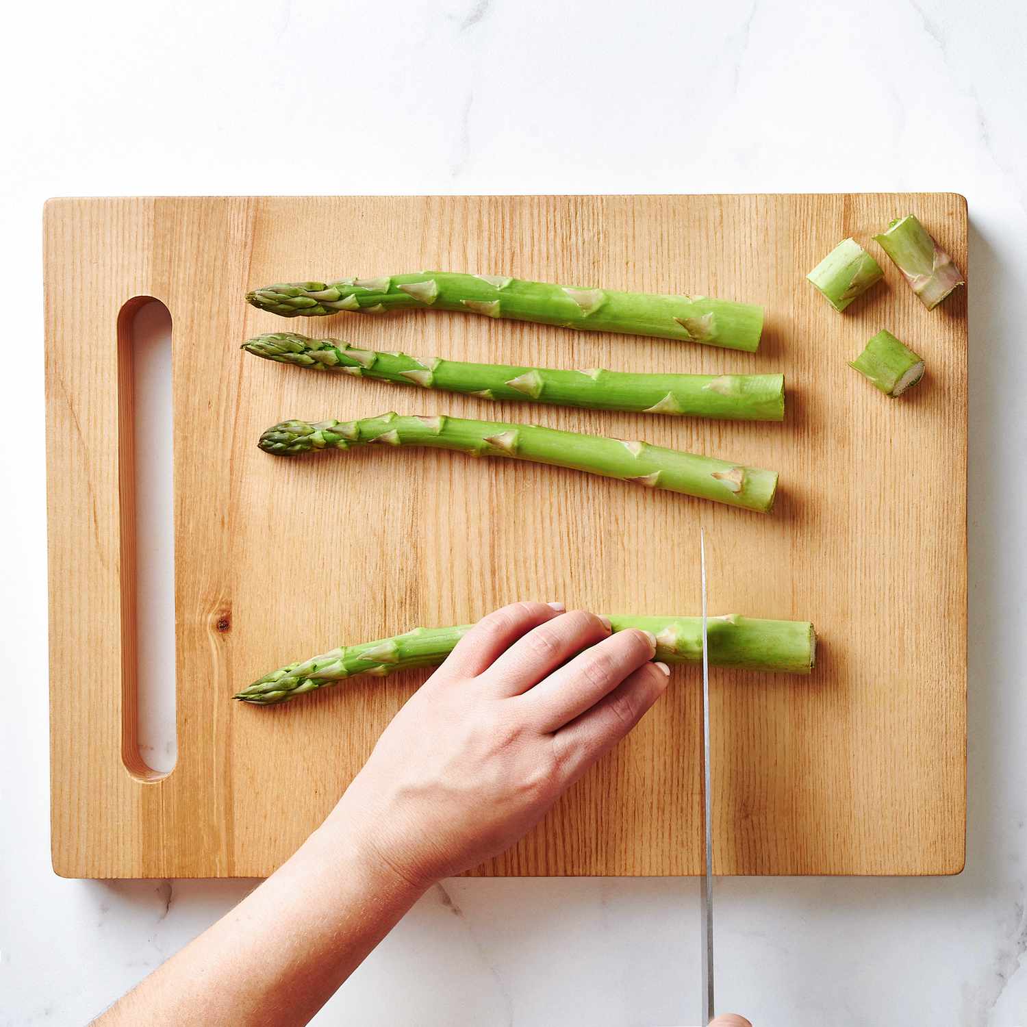 Close up of hands cutting the ends off asparagus