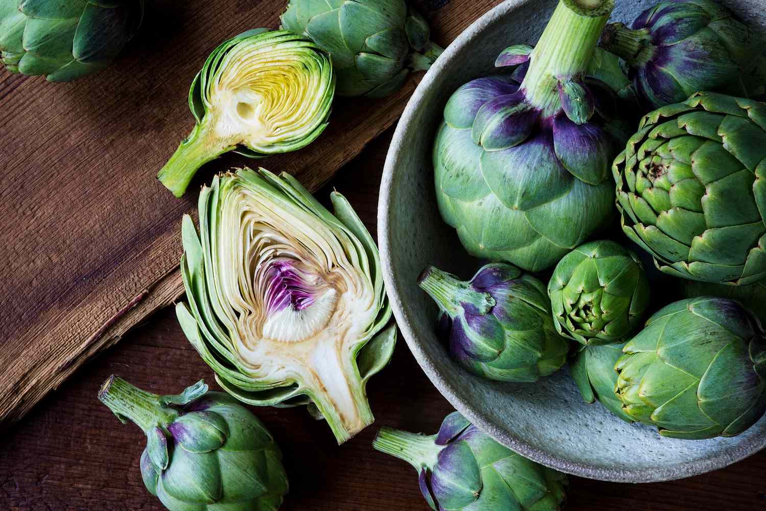 Artichokes on a wood surface and in a bowl