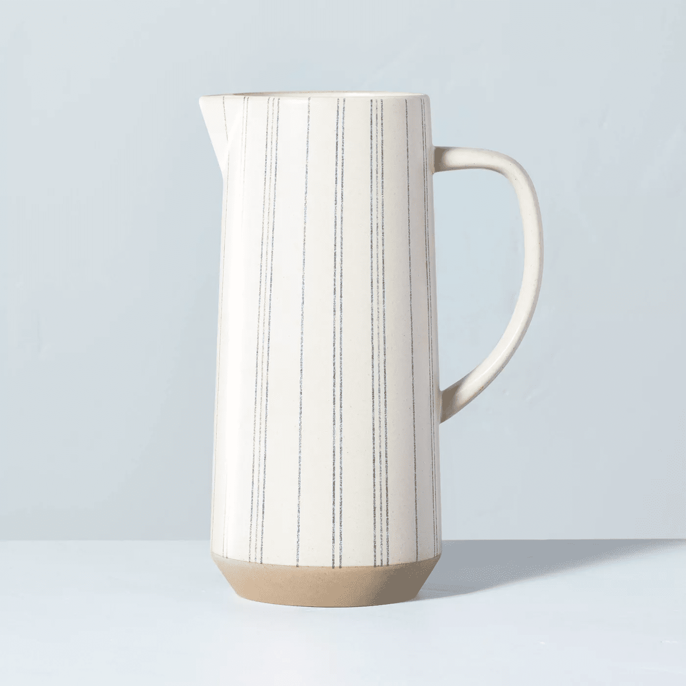 white and blue striped pitcher on light blue backdrop