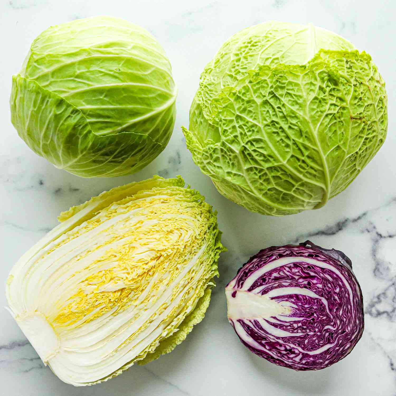 A variety of types of cabbage on a marble surface