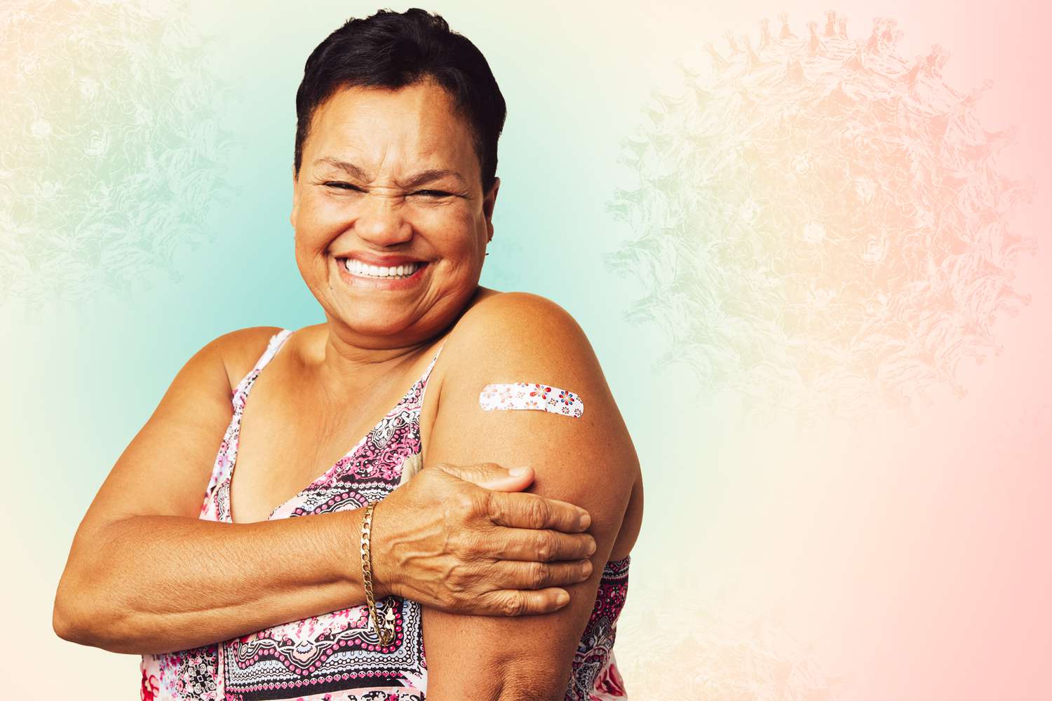 A woman smiling with a bandaid on her shoulder on a designed background