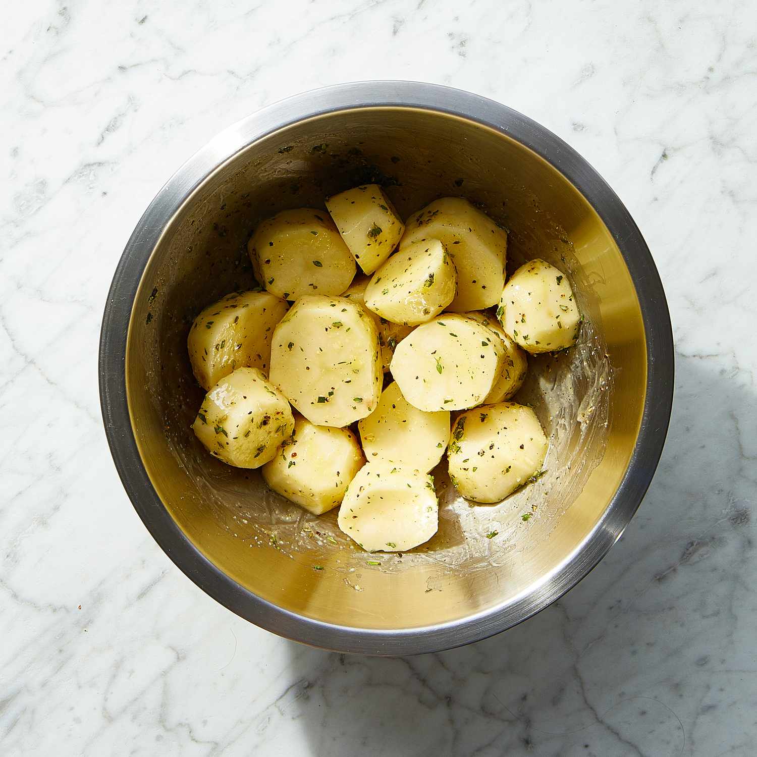 potato slices in a metal bowl with oil and seasoning