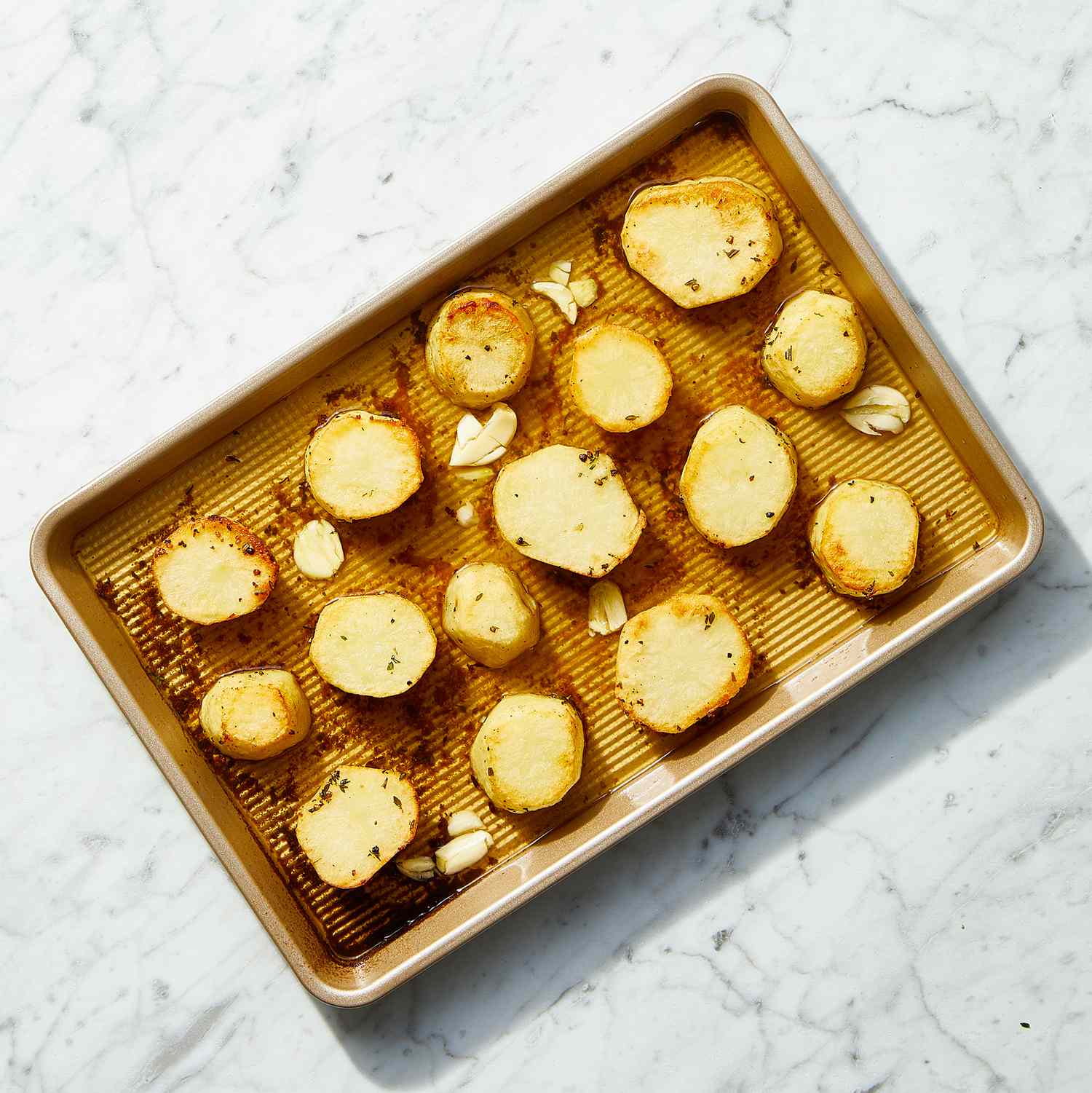 roasted potatoes on a baking sheet with broth and garlic