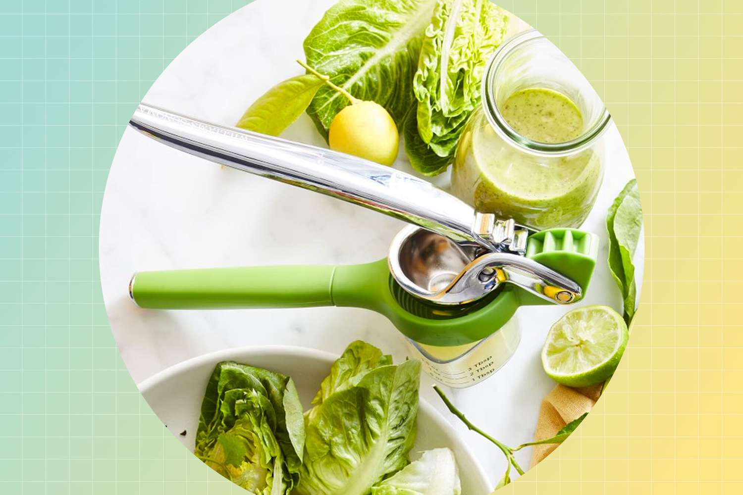 Metal and plastic lime press on a white counter with salad ingredients and a green dressing