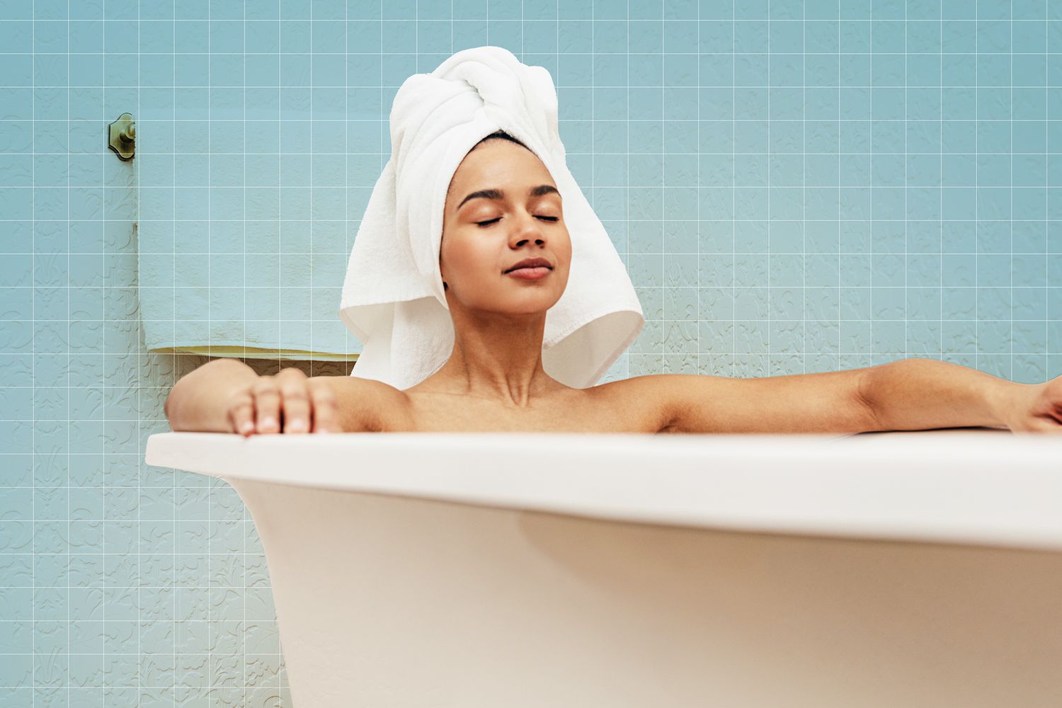 Woman with white towel on her head relaxing in bath with eyes closed