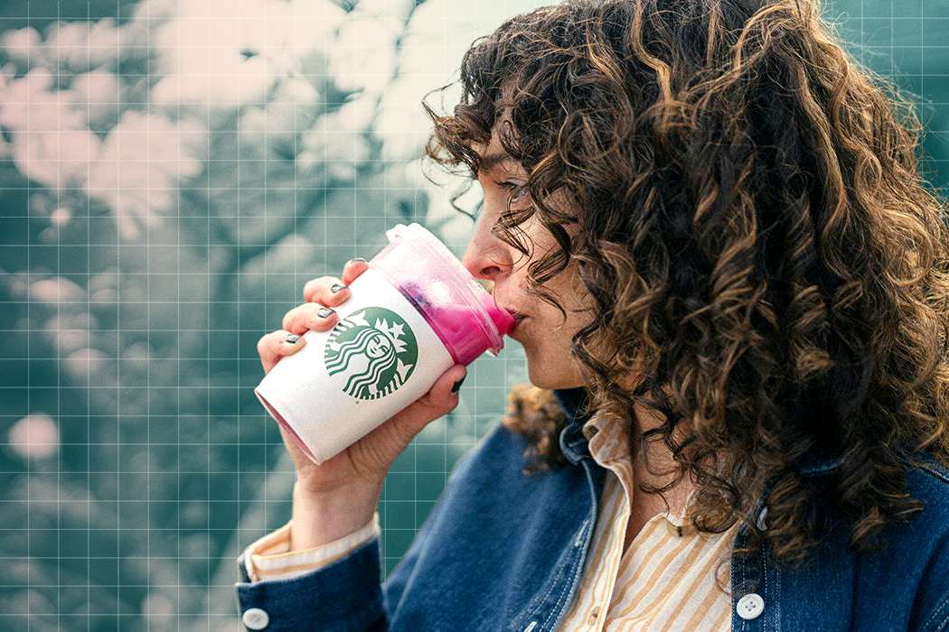 woman drinking a pink drink out of a Starbucks cup