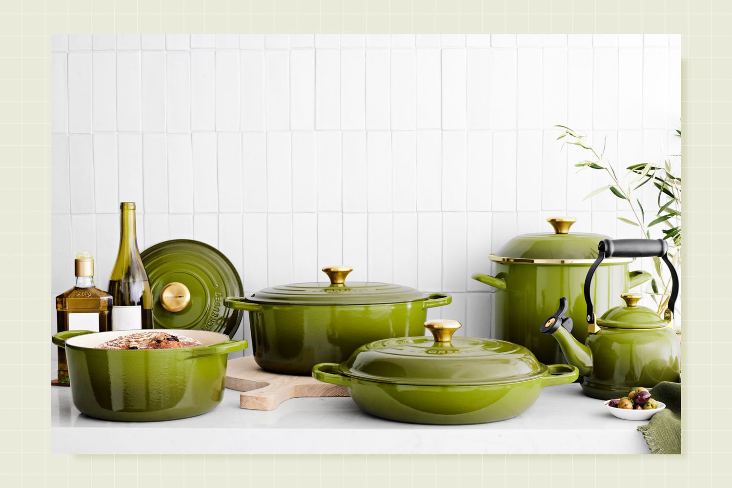 Williams Sonoma x Le Creuset Olive collection on a designed background