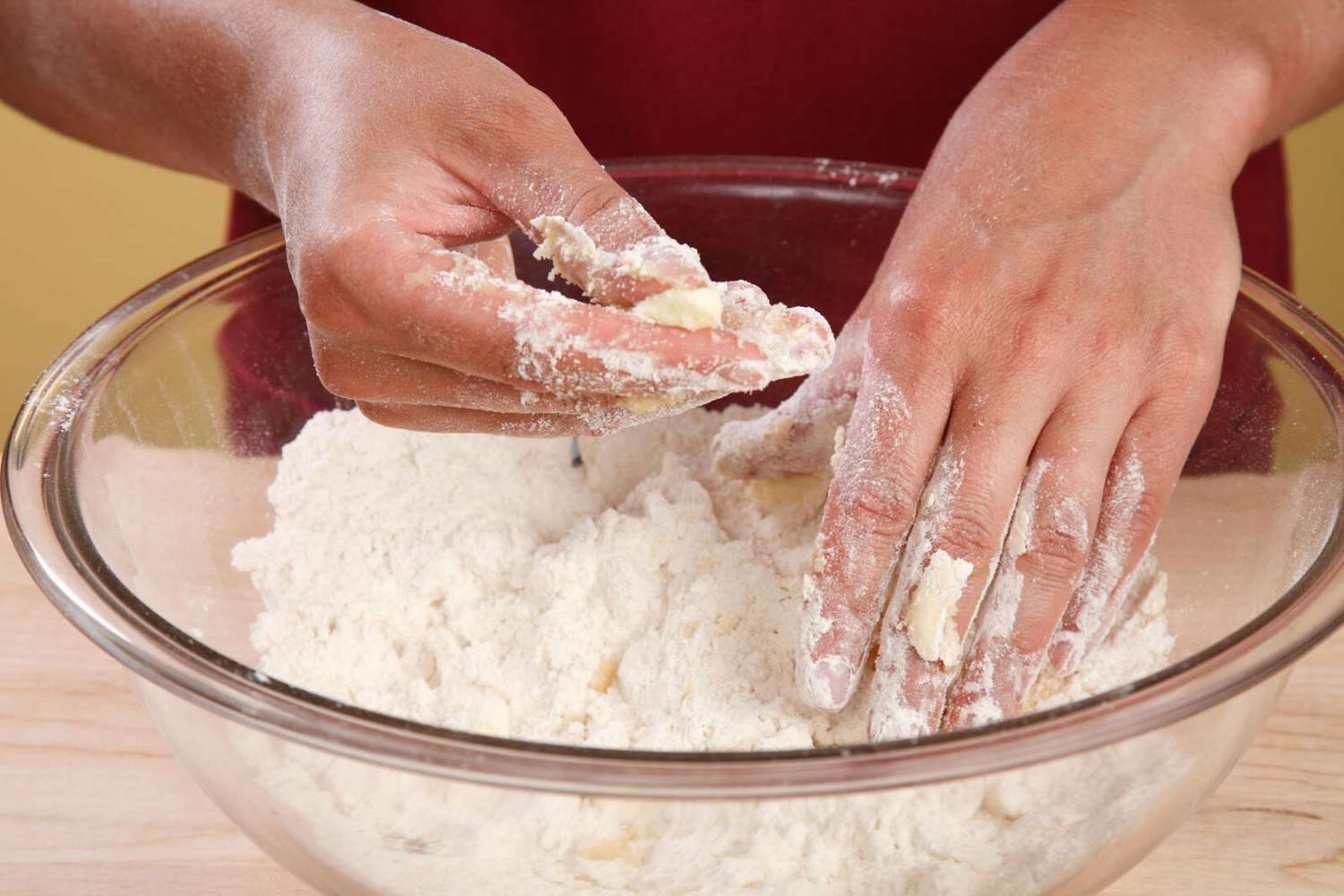 hands working butter into a bowl of flour