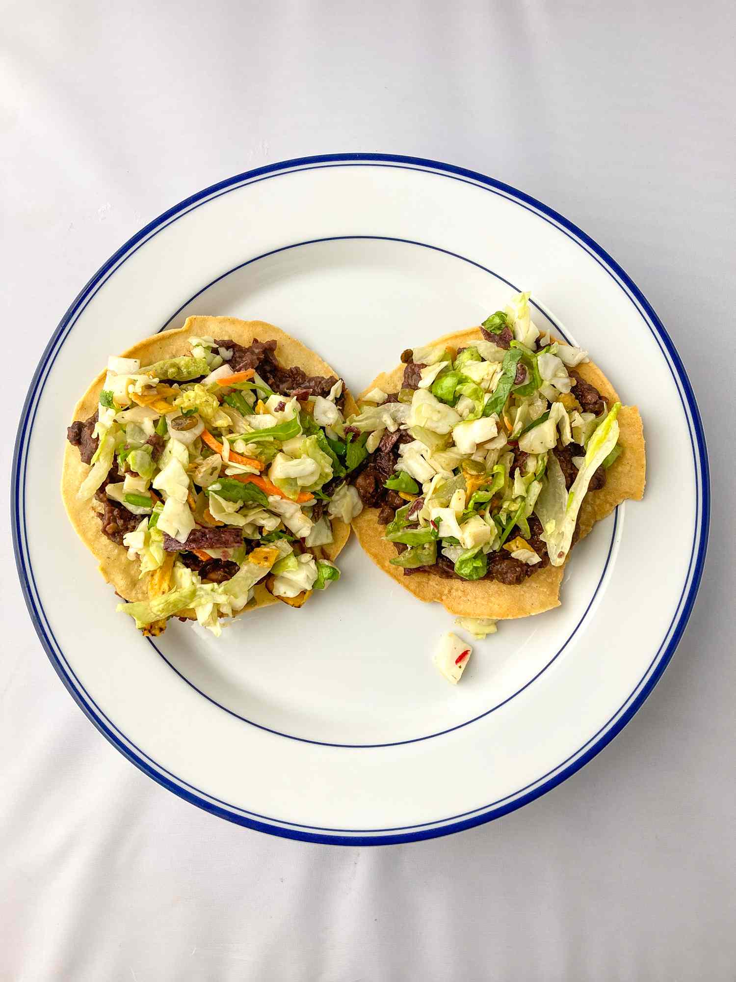 two tostadas on a white plate with a blue rim