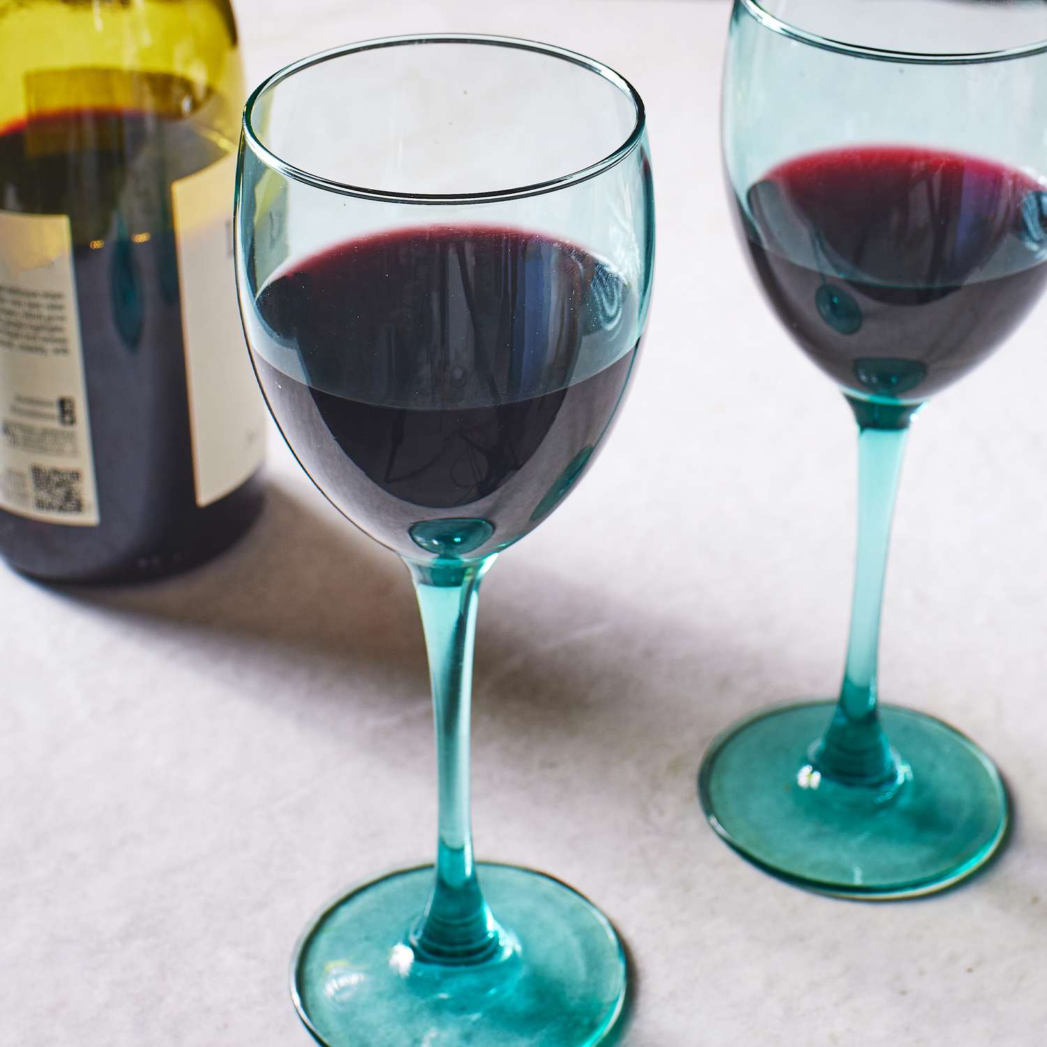 two glasses of red wine beside a bottle of wine