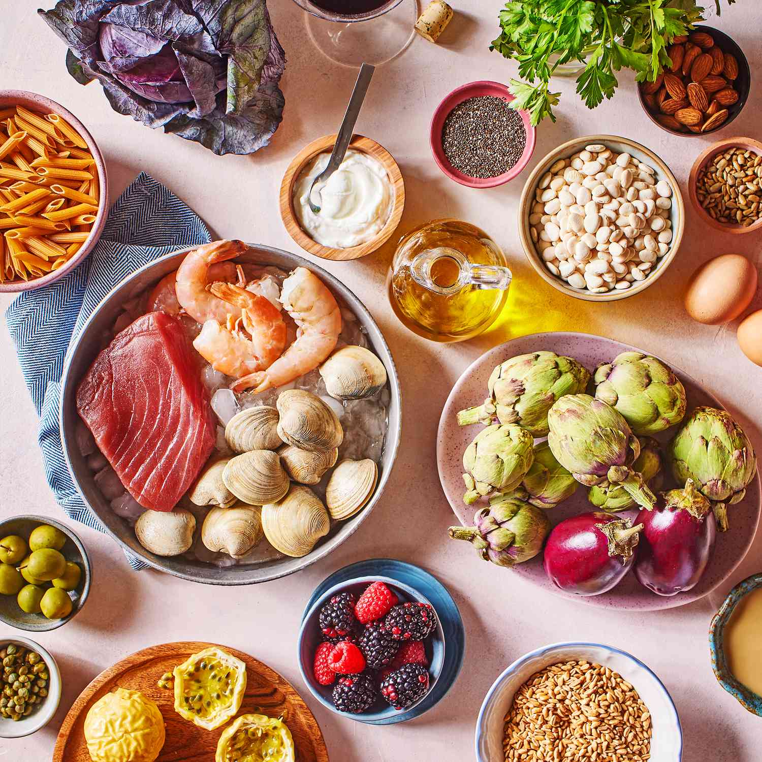 a group of Mediterranean Diet foods that include steak, shrimp, berries, artichokes, yogurt, seeds, pasta, nuts, eggs, and olive oil