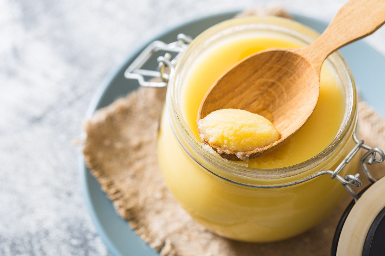 a photo of a jar of ghee with a wooden spoon scooping out some