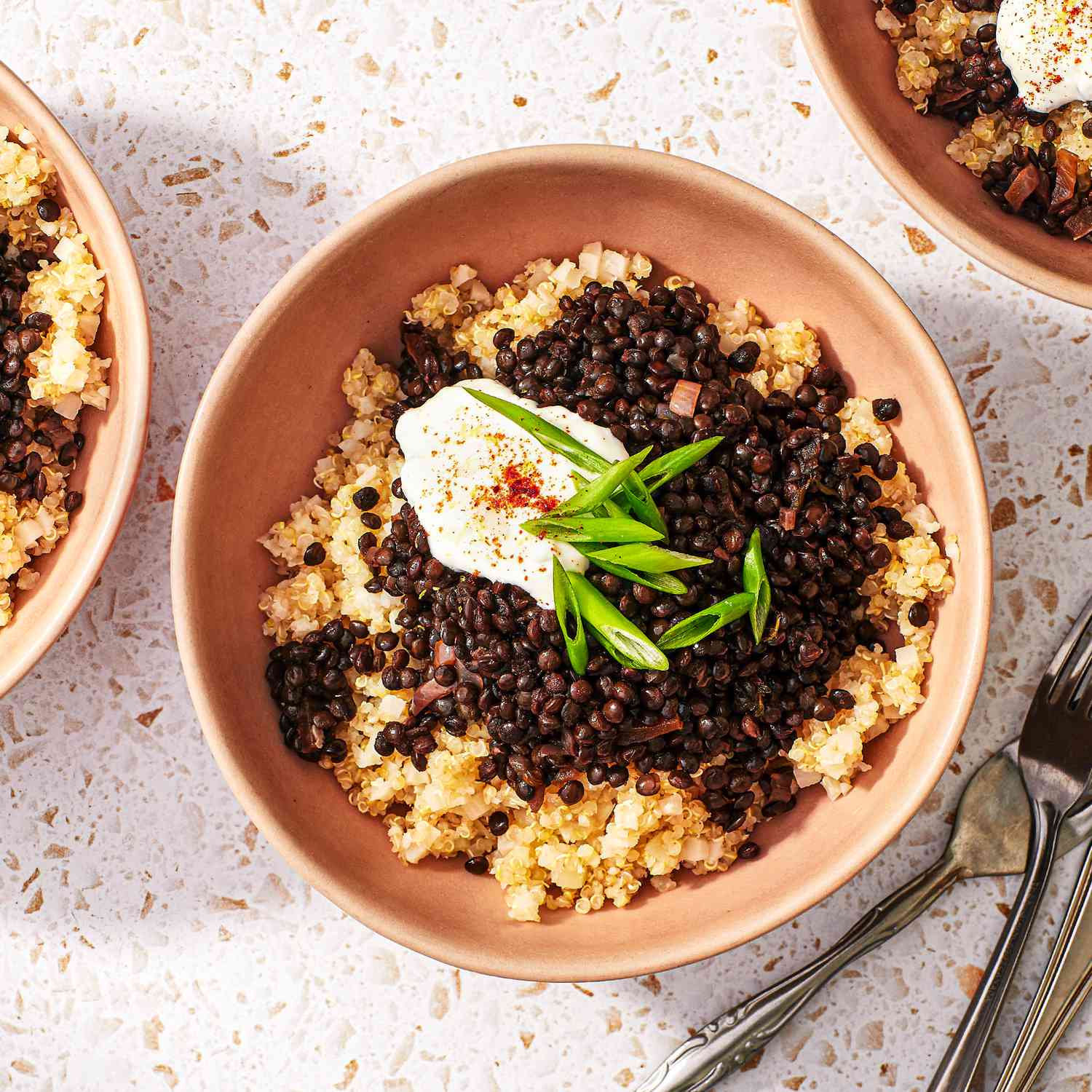 a recipe photo of the Braised Black Lentil Bowls served in a bowl and topped with sour cream and chives