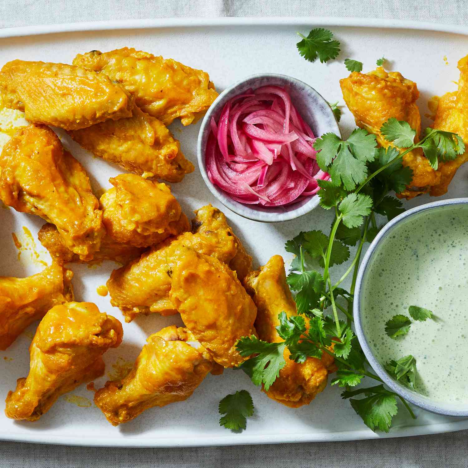 Chicken Wings with Peruvian Yellow Hot Sauce, Cilantro Crema & Pickled Onions