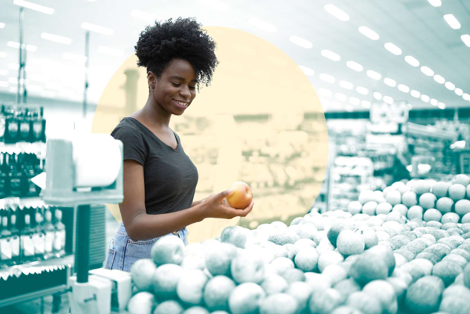 Portrait of smiling young woman choosing apple in supermarket