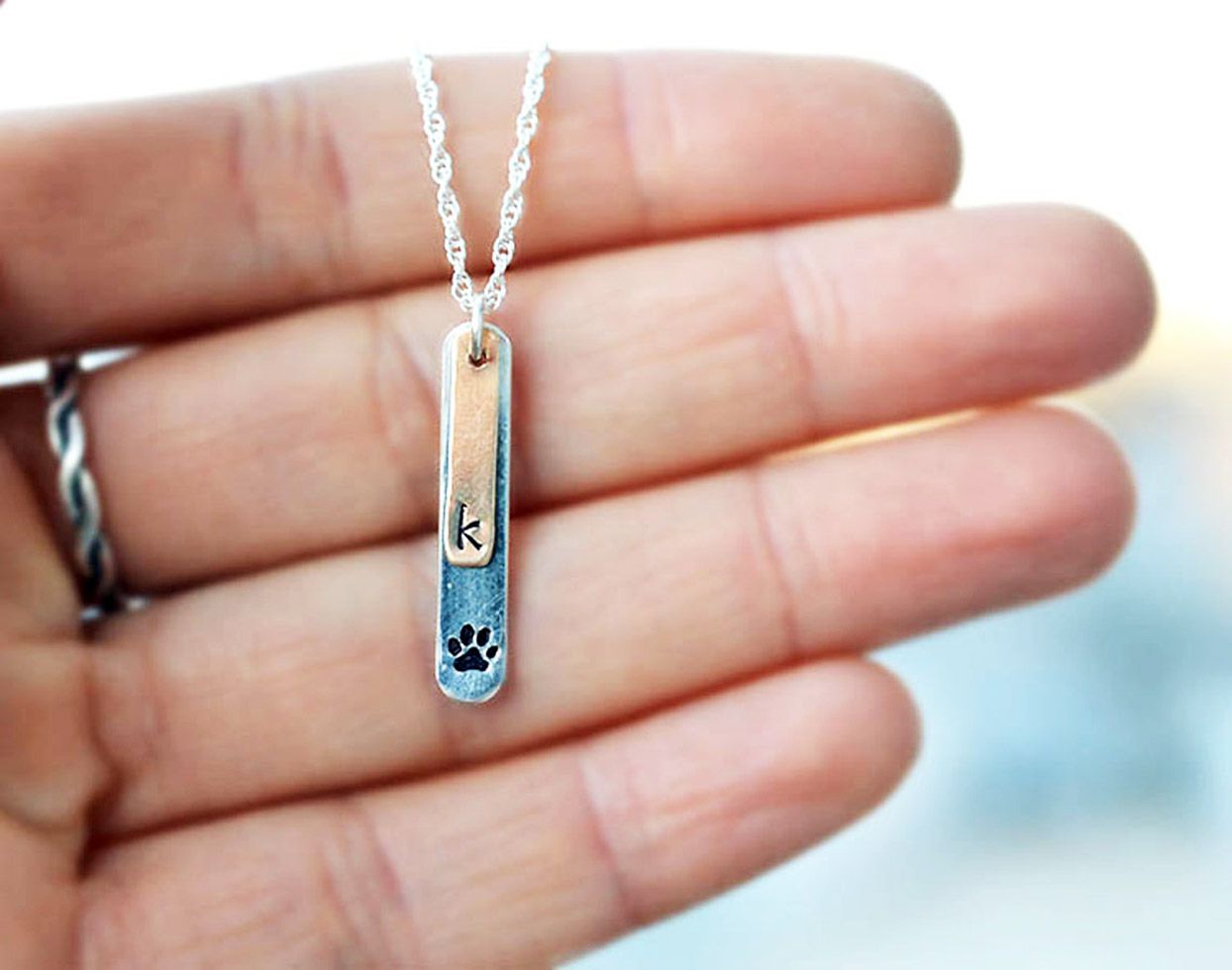 Close-up of dog paw necklace with personalized initial