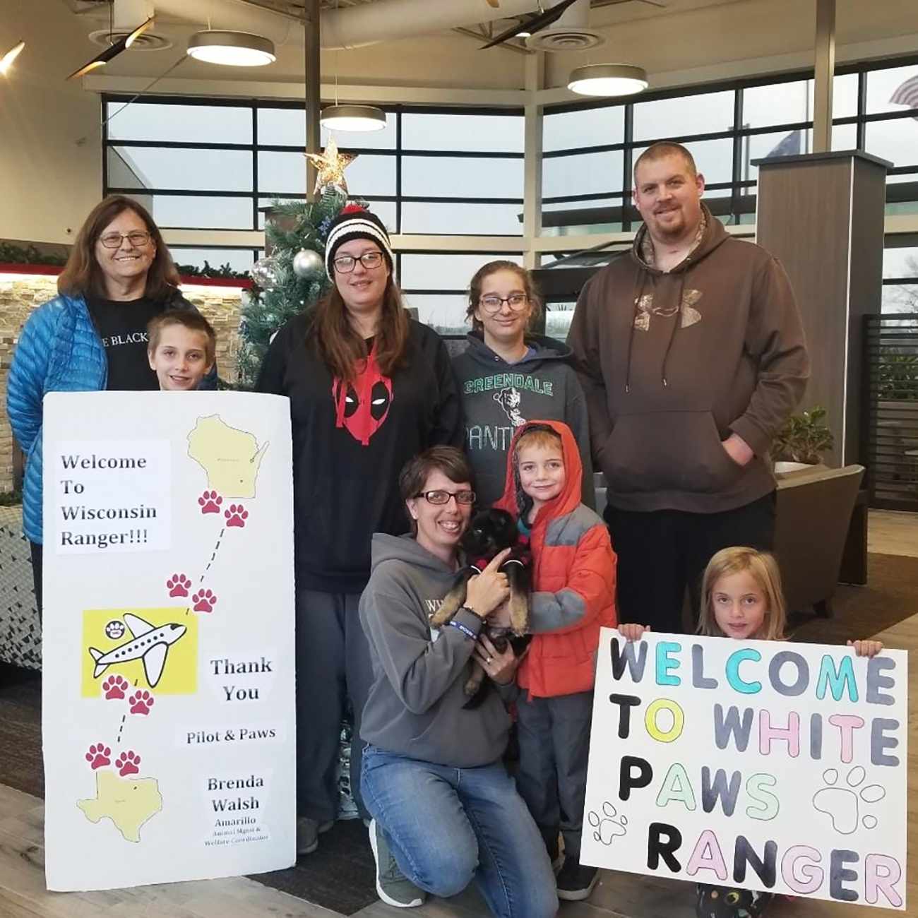 family in airport with welcome home signs