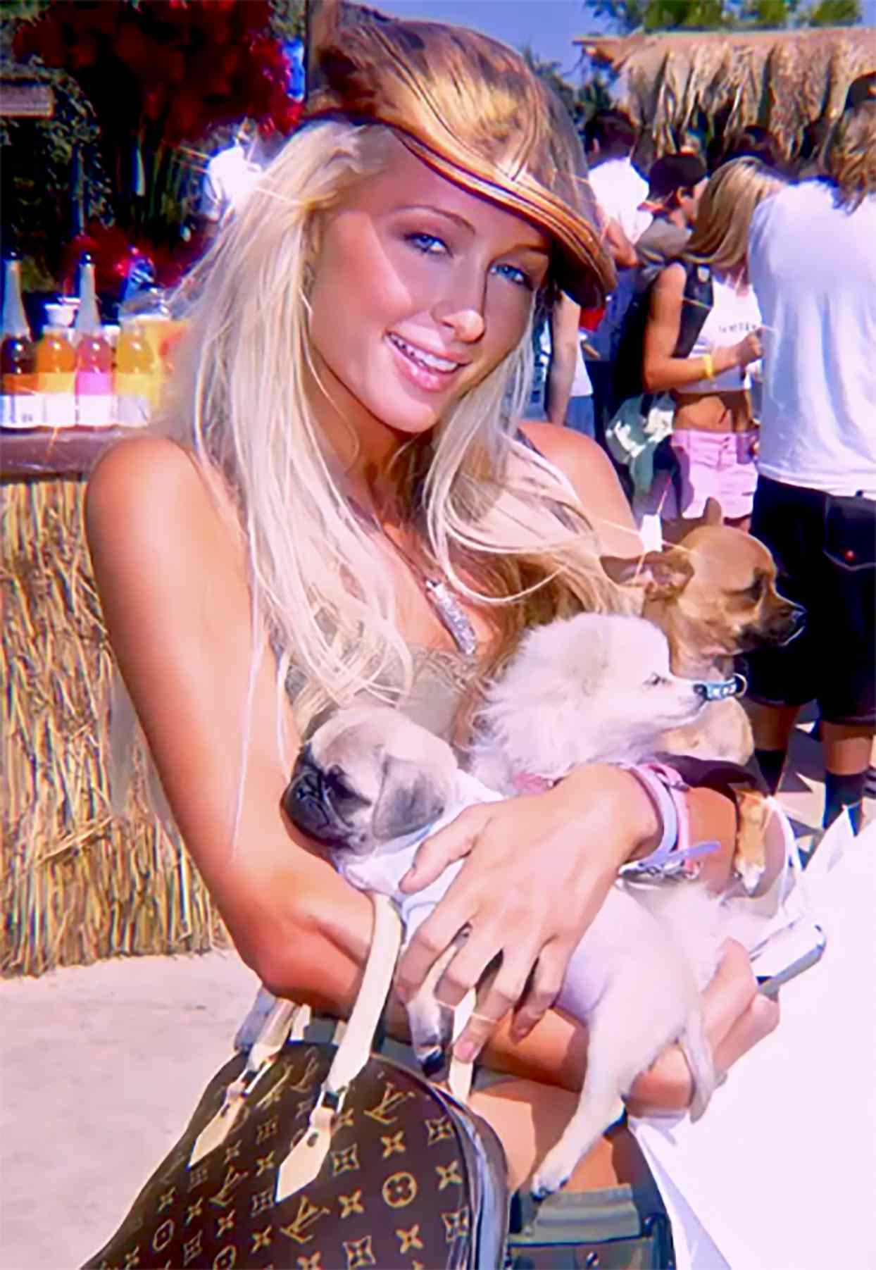 Photo of celebrity Paris Hilton holding three small dogs in her arms
