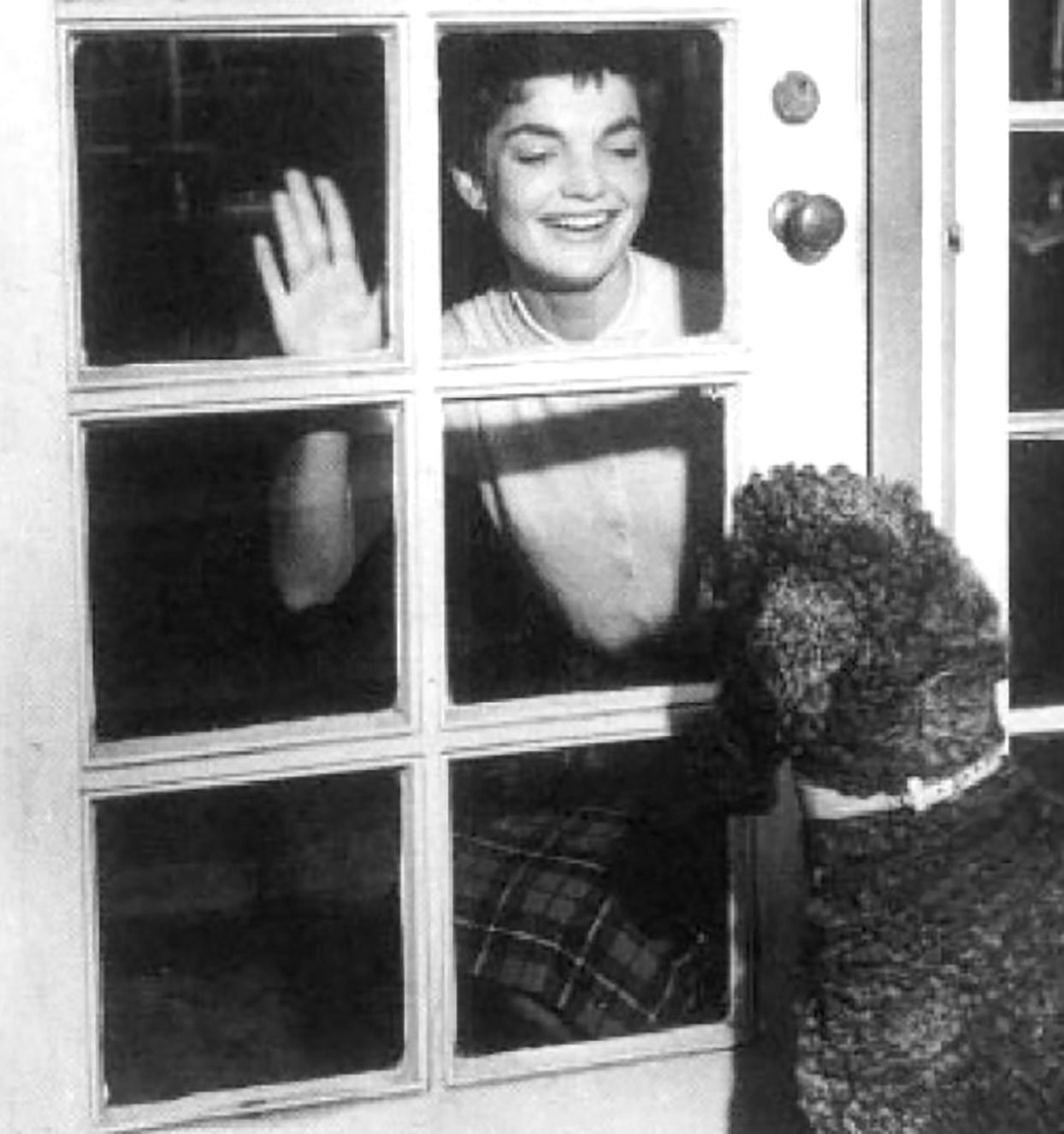 Jackie Kennedy looking through window at her black standard poodle