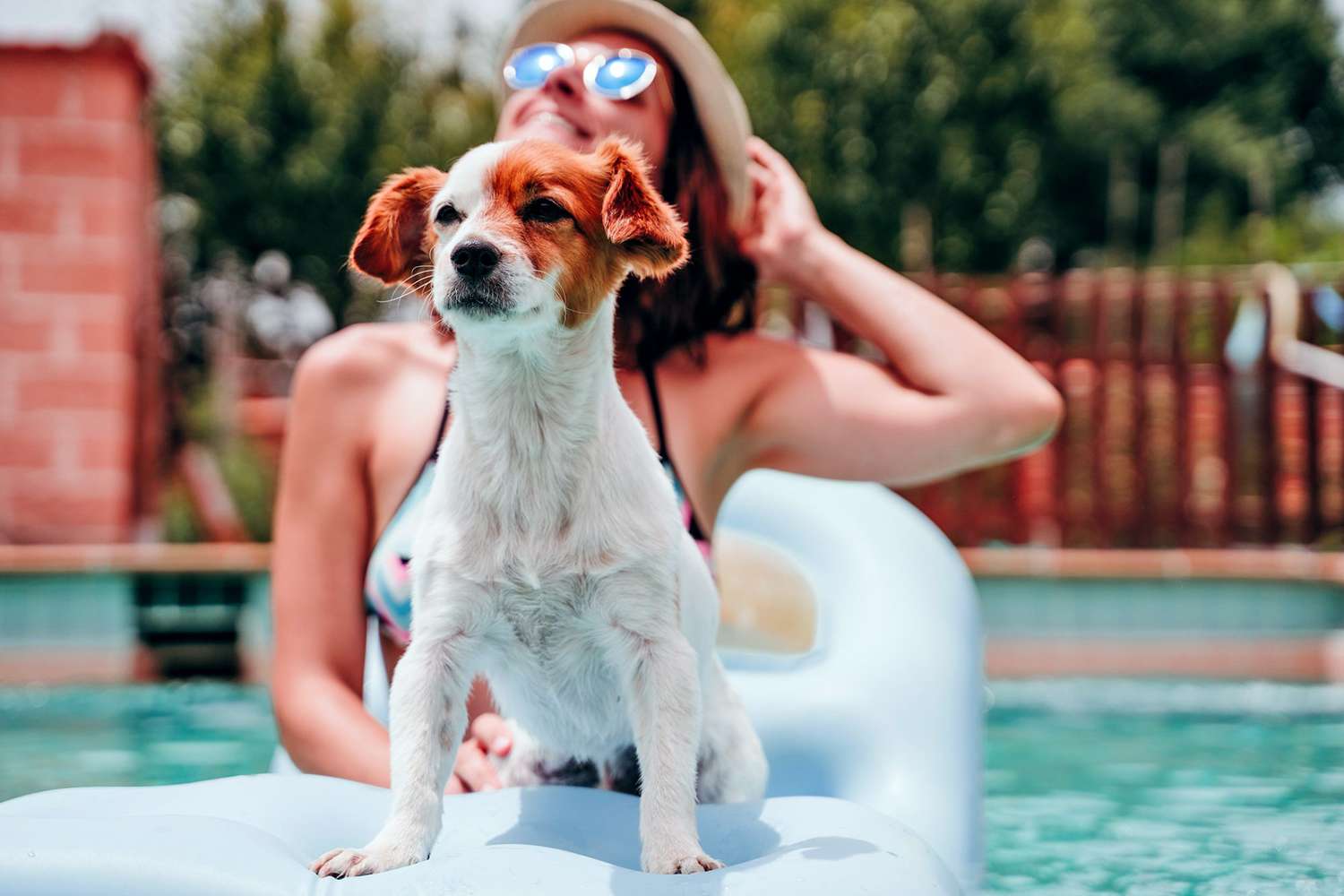 Woman lounging on a raft in her pool with her dog; summer dog names