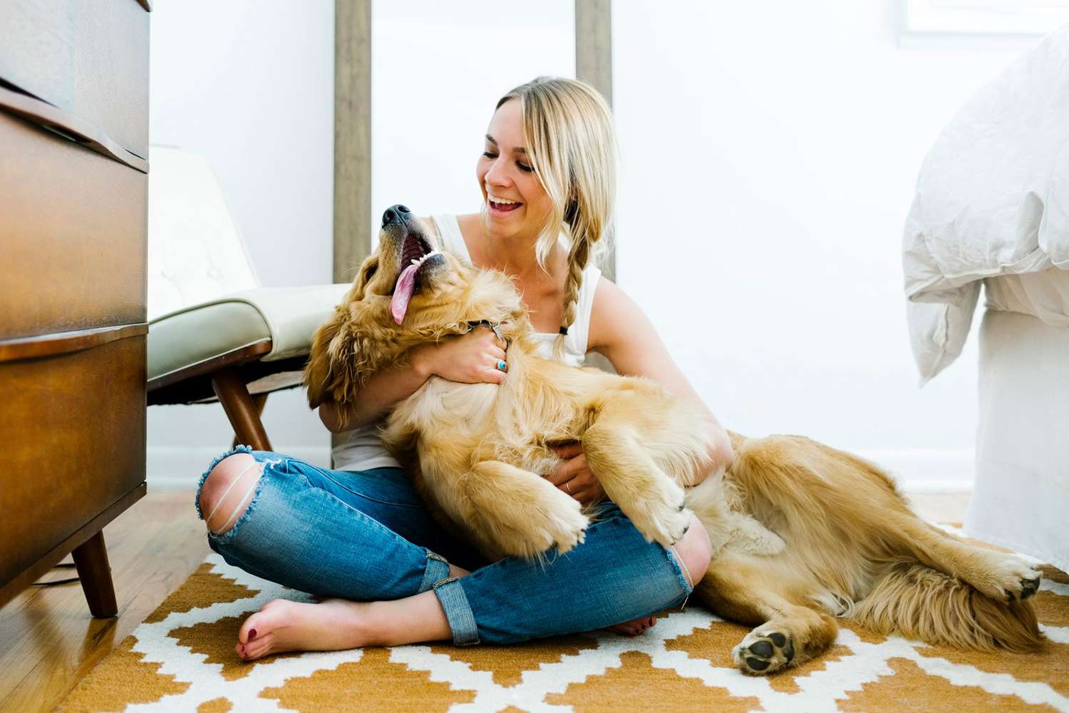 woman cuddles on the floor with a golden retriever, one of the most affectionate dog breeds