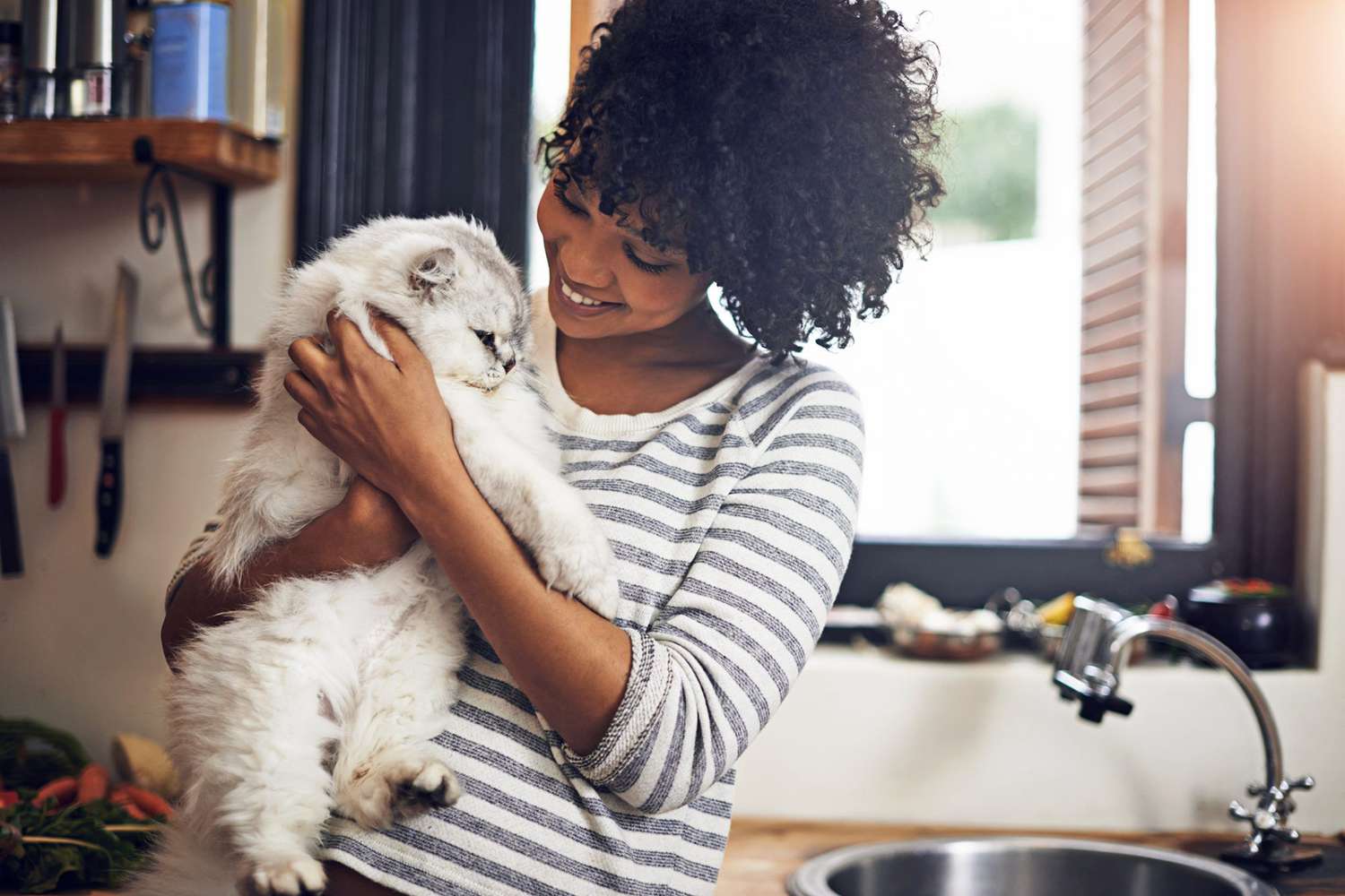 woman holding cat in her kitchen; is baking soda safe for cats?